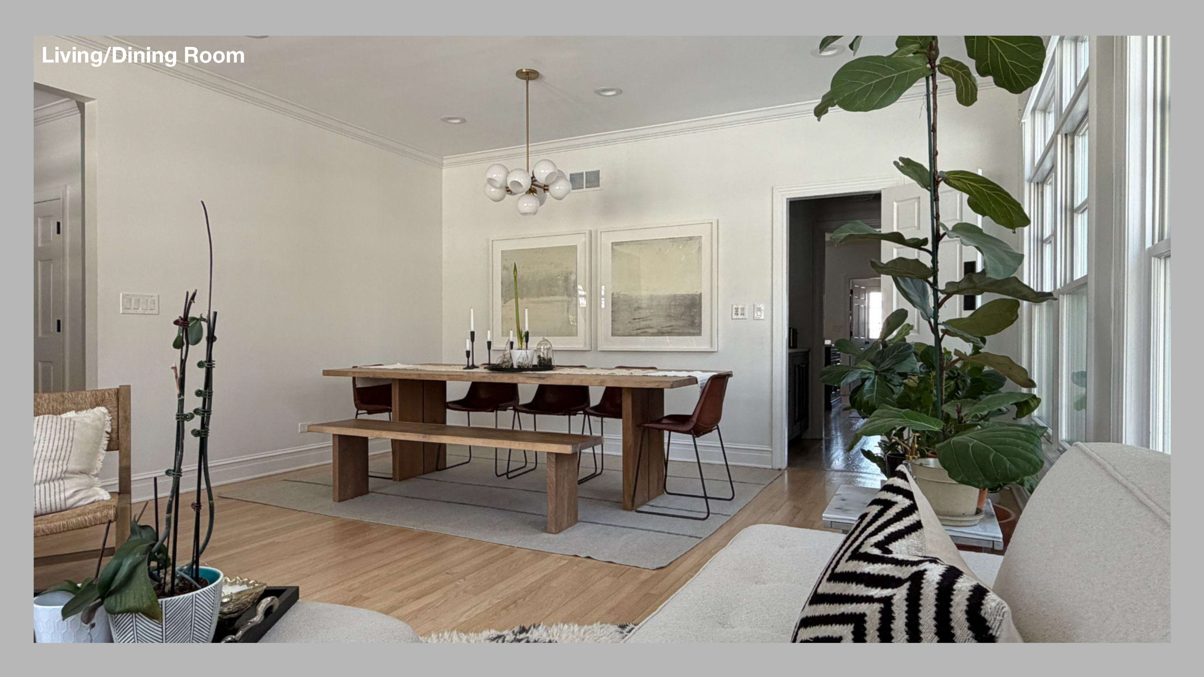 A spacious living and dining room features a large wooden table surrounded by leather chairs, with a plant in the corner and a comfortable seating area nearby.