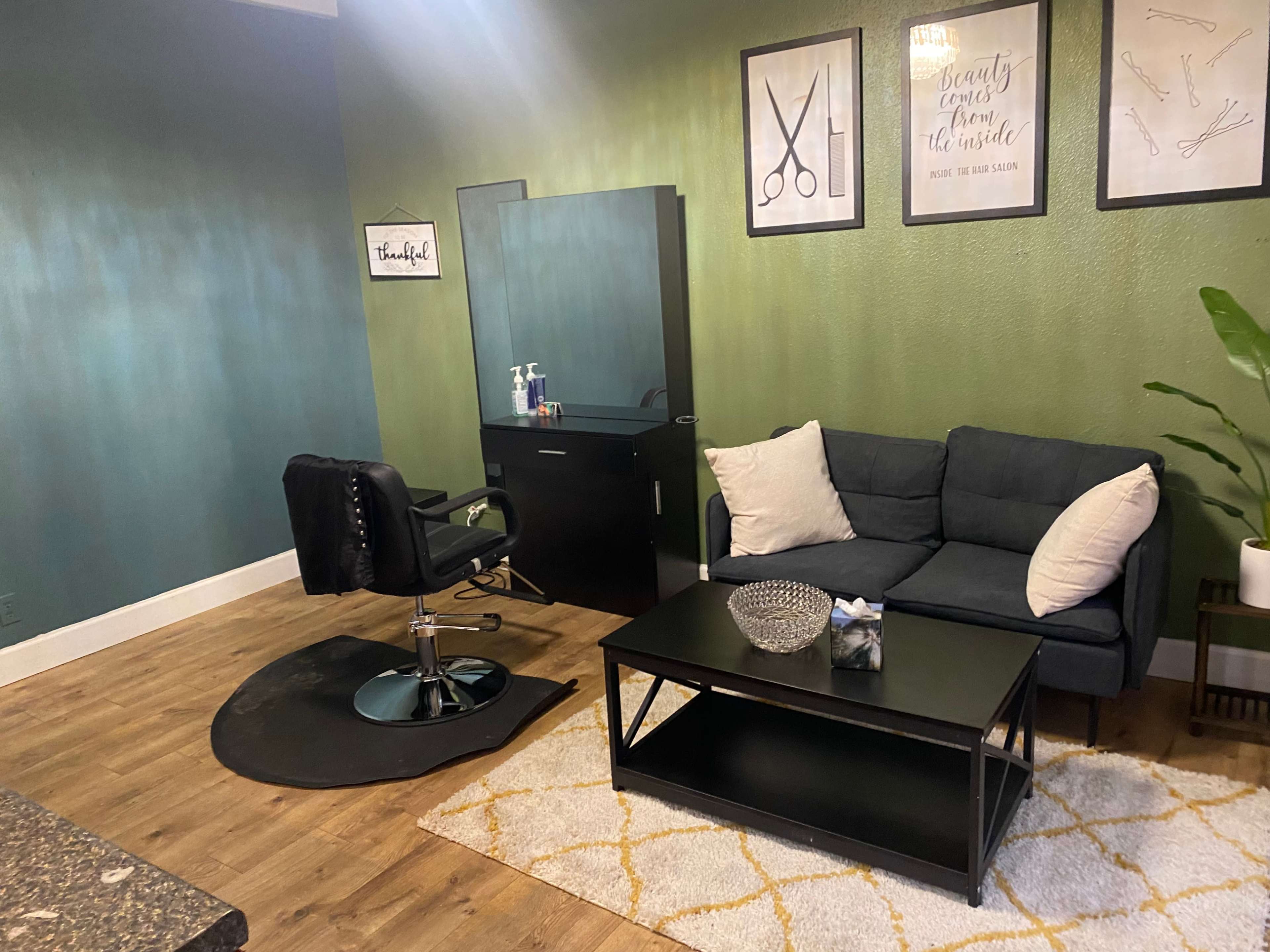 A hair salon interior featuring a styling chair, a mirror, a couch, and a coffee table.