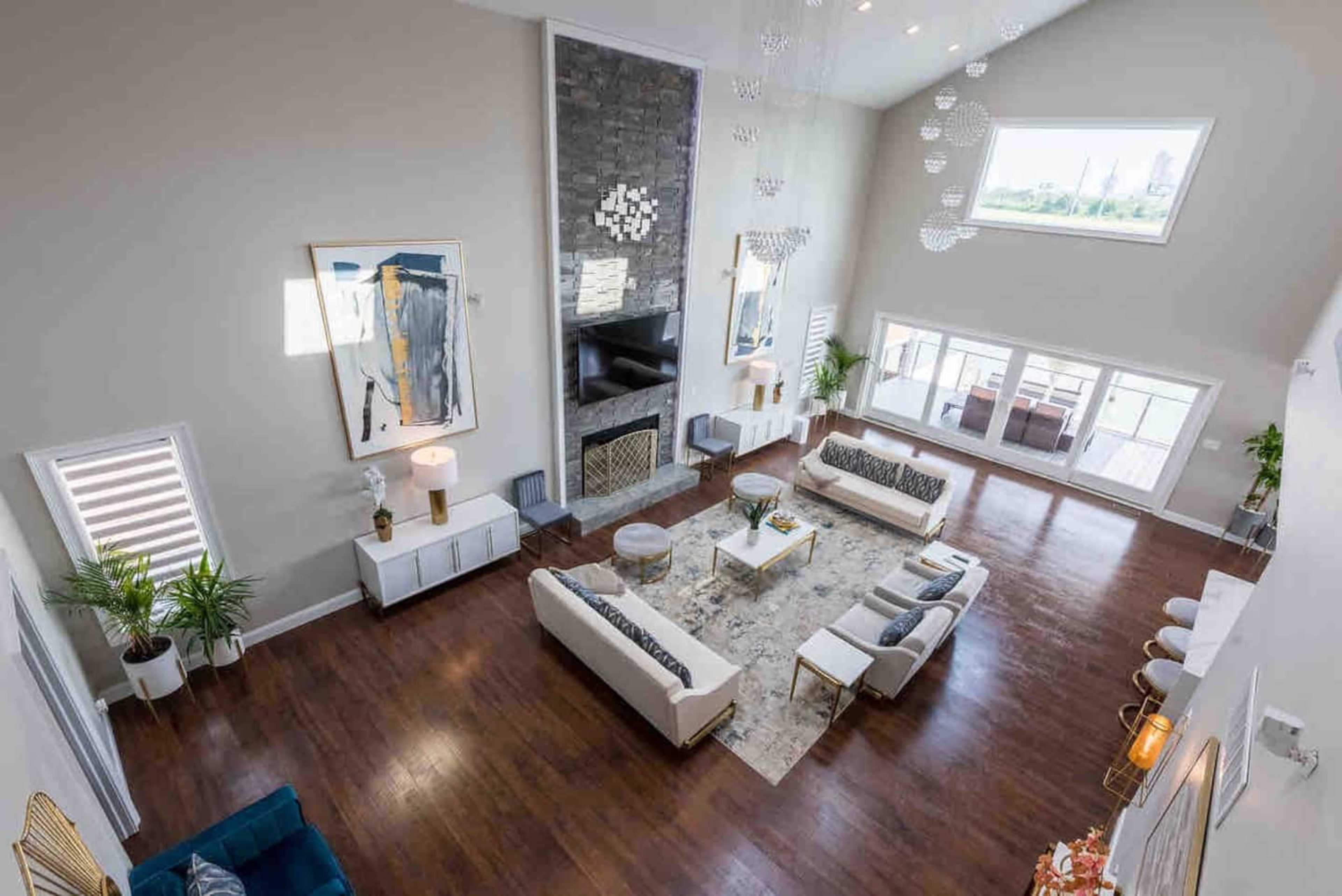 A spacious living room with high ceilings, large windows, contemporary furniture, and a stone fireplace.