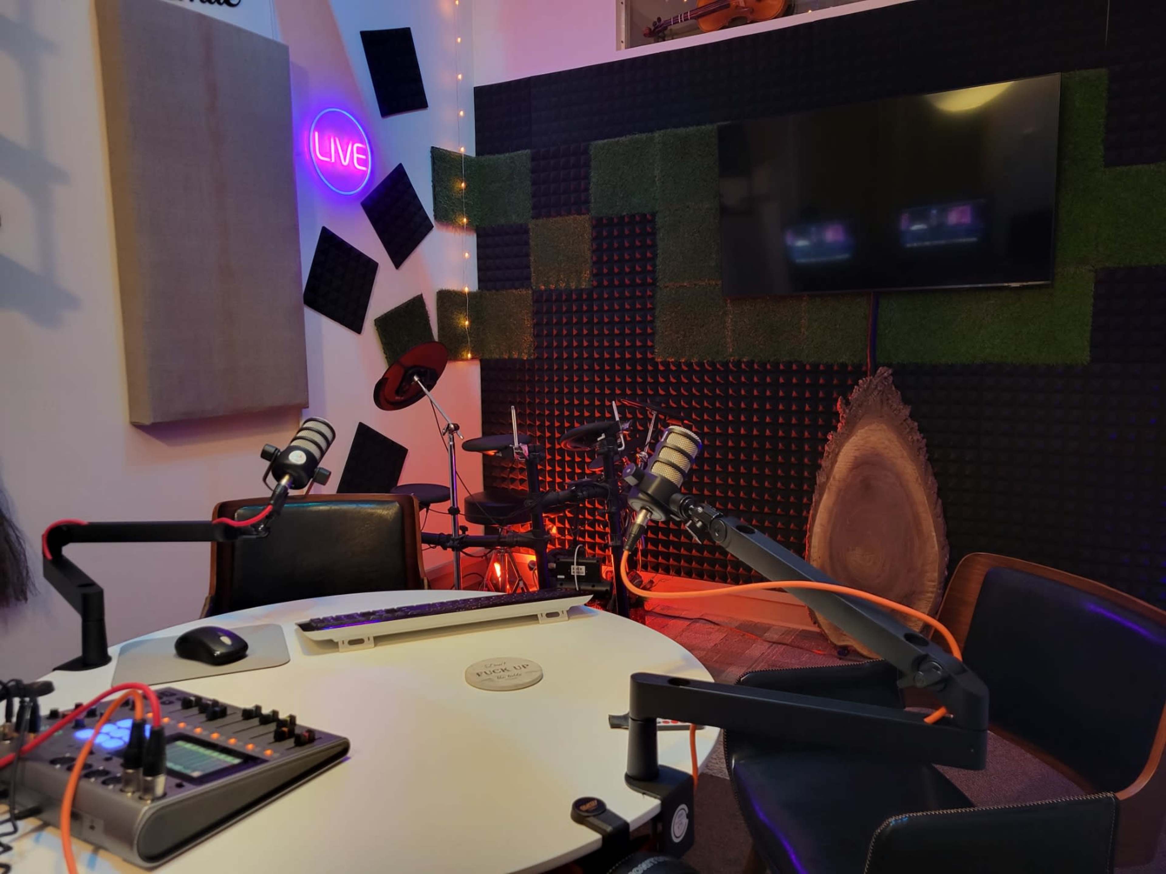 A recording studio setup with a round table, microphones, audio equipment, and soundproofing panels on the walls.