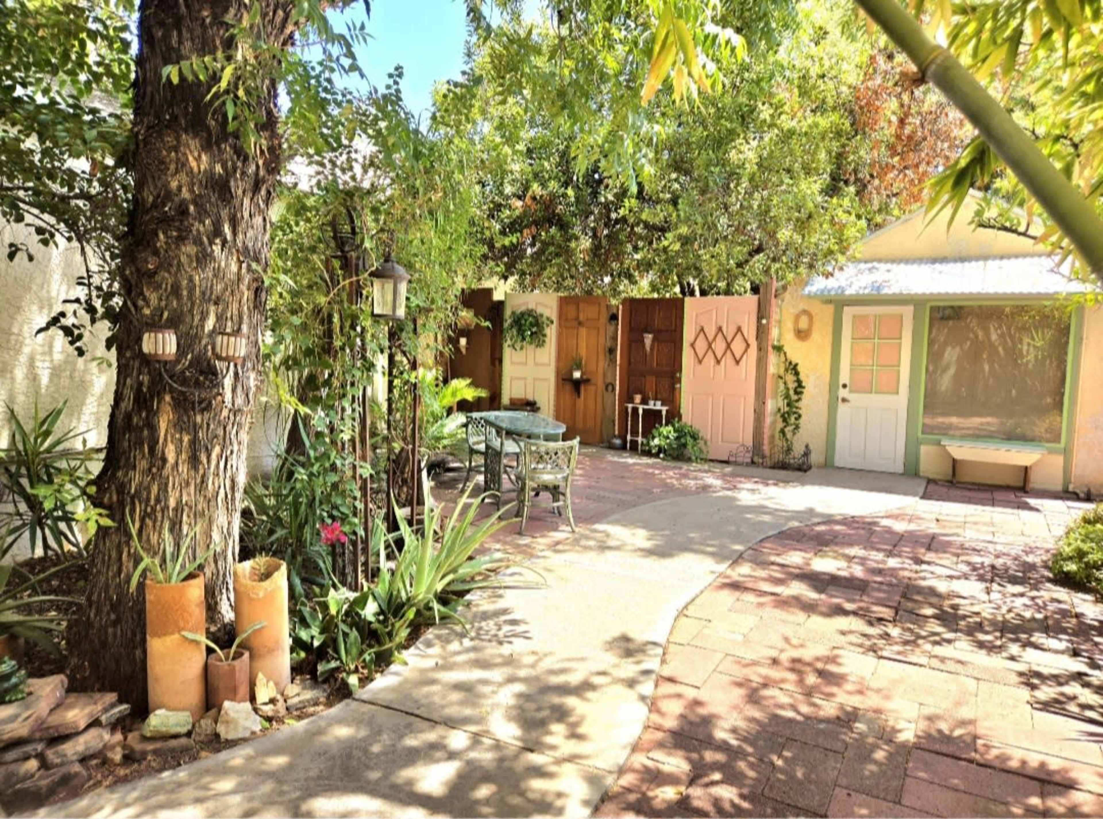 The image shows a garden path winding through lush greenery with a combination of colorful doors in the background.