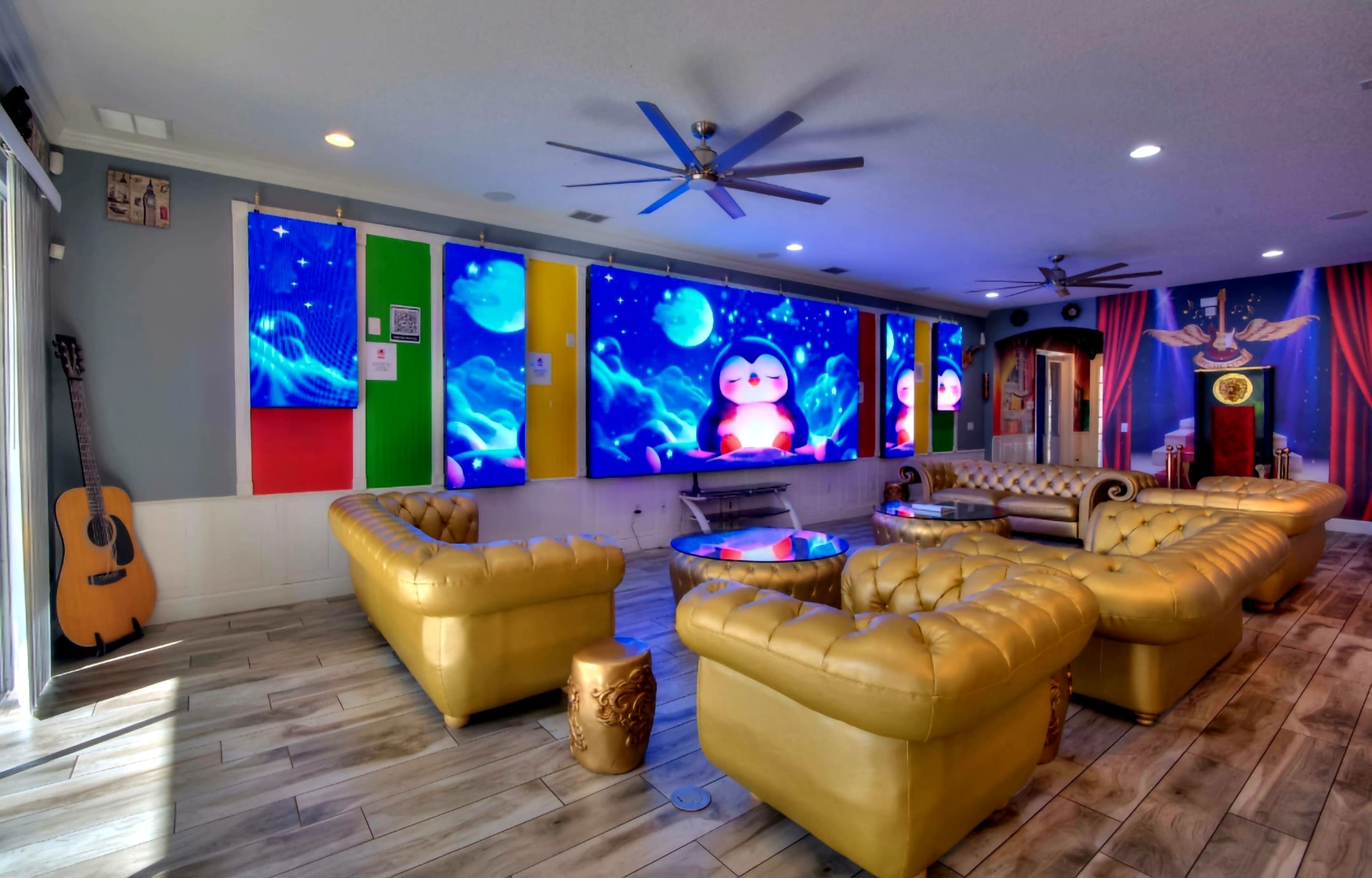 The scene shows a brightly lit lounge area featuring golden couches, large colorful wall displays, and a guitar leaning against the wall.