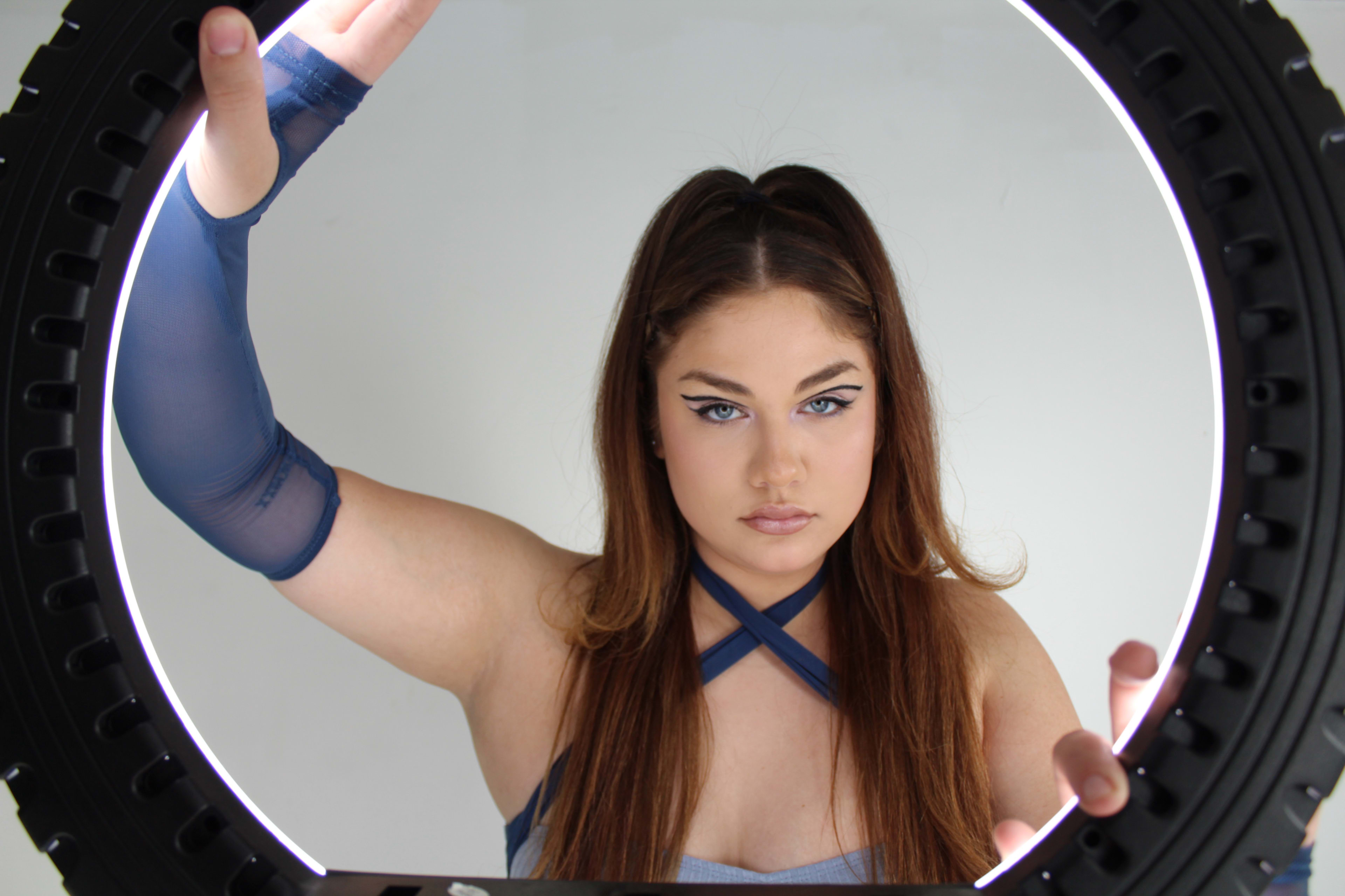 A woman with her arm around a neon tyre in a portrait.