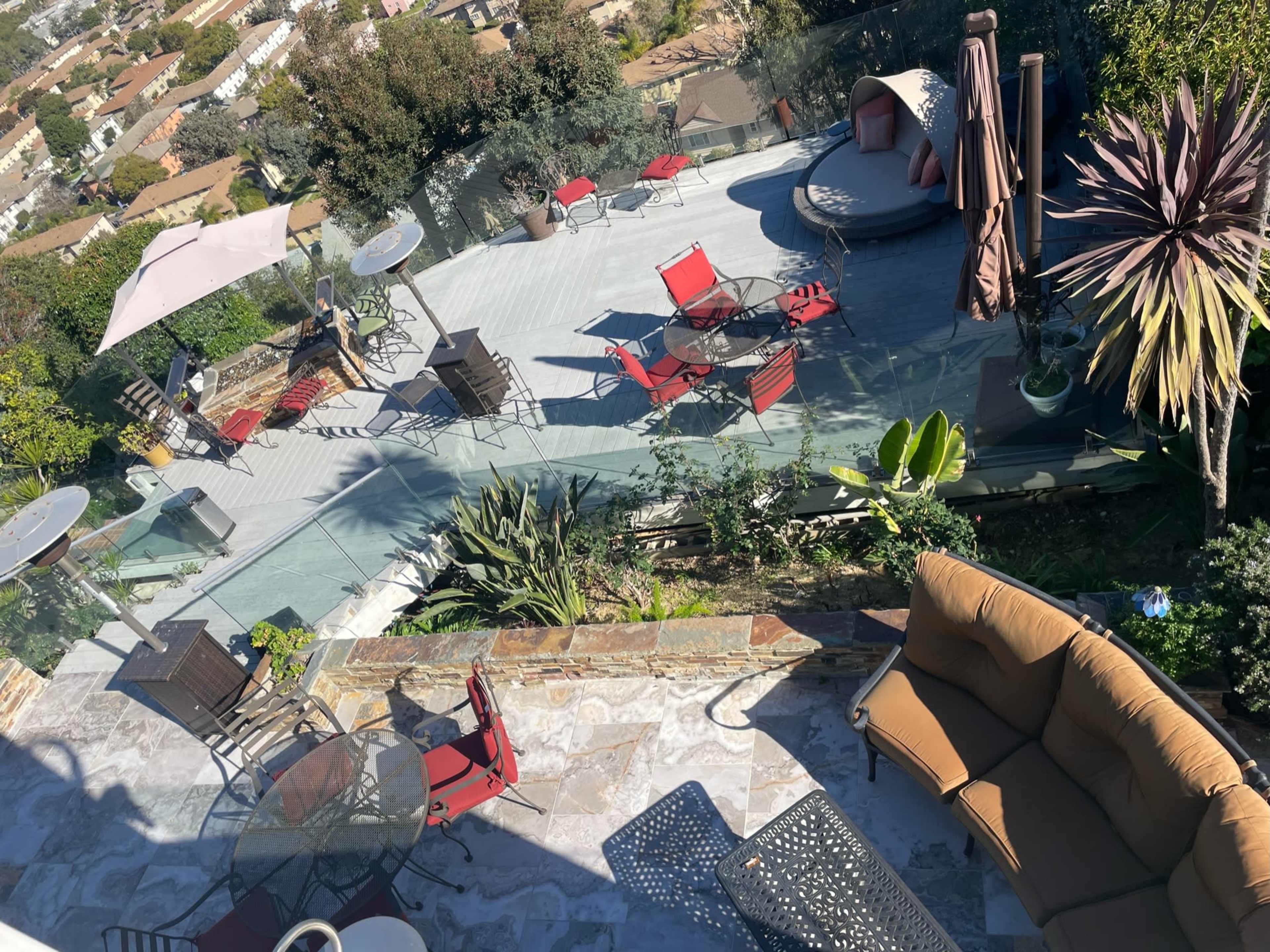 A multi-level outdoor patio with various seating areas, including chairs and tables, overlooking a neighborhood below.
