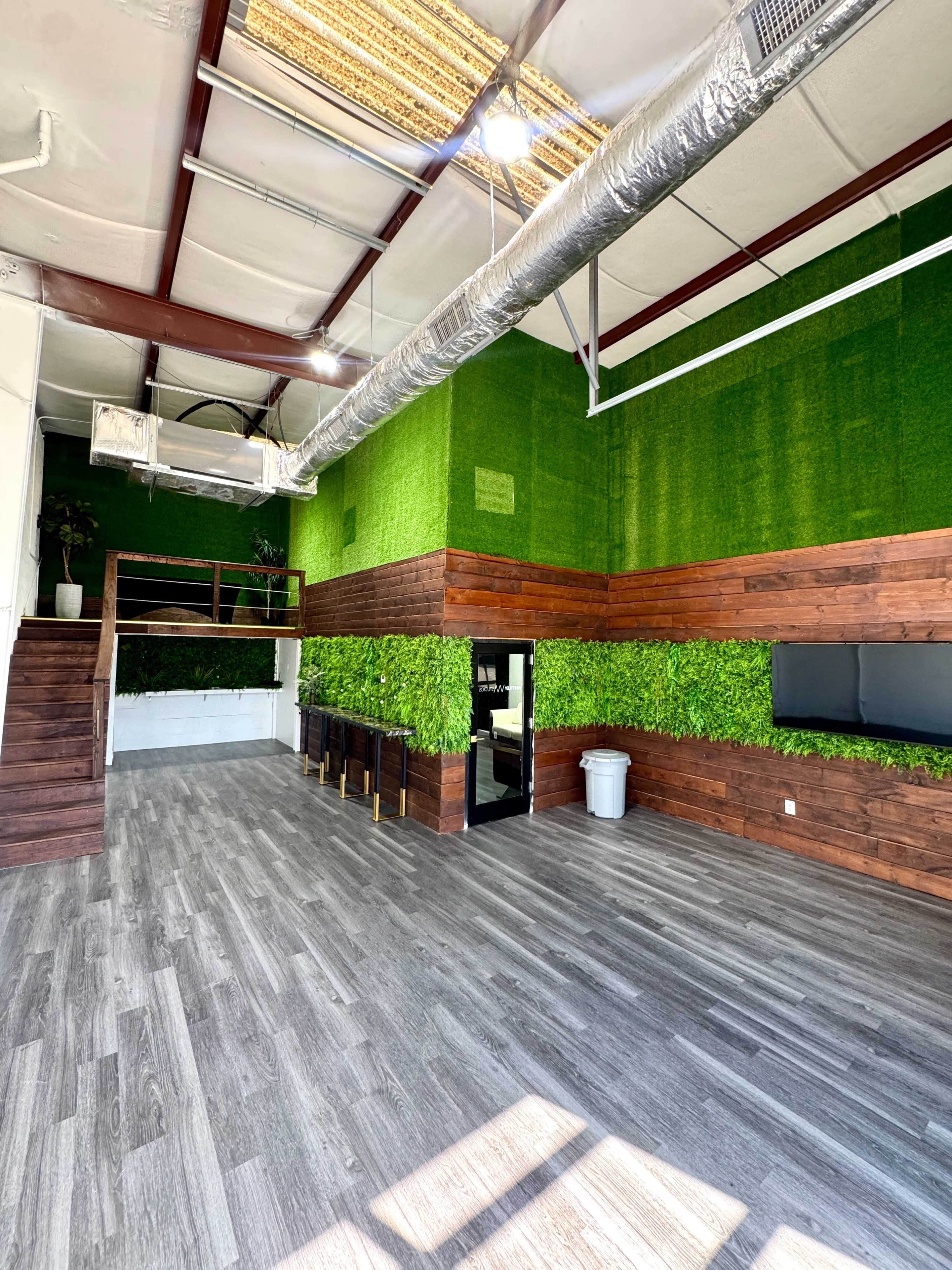 The image shows an interior space featuring green wall panels, wooden accents, and a modern design with steps leading to a loft area.