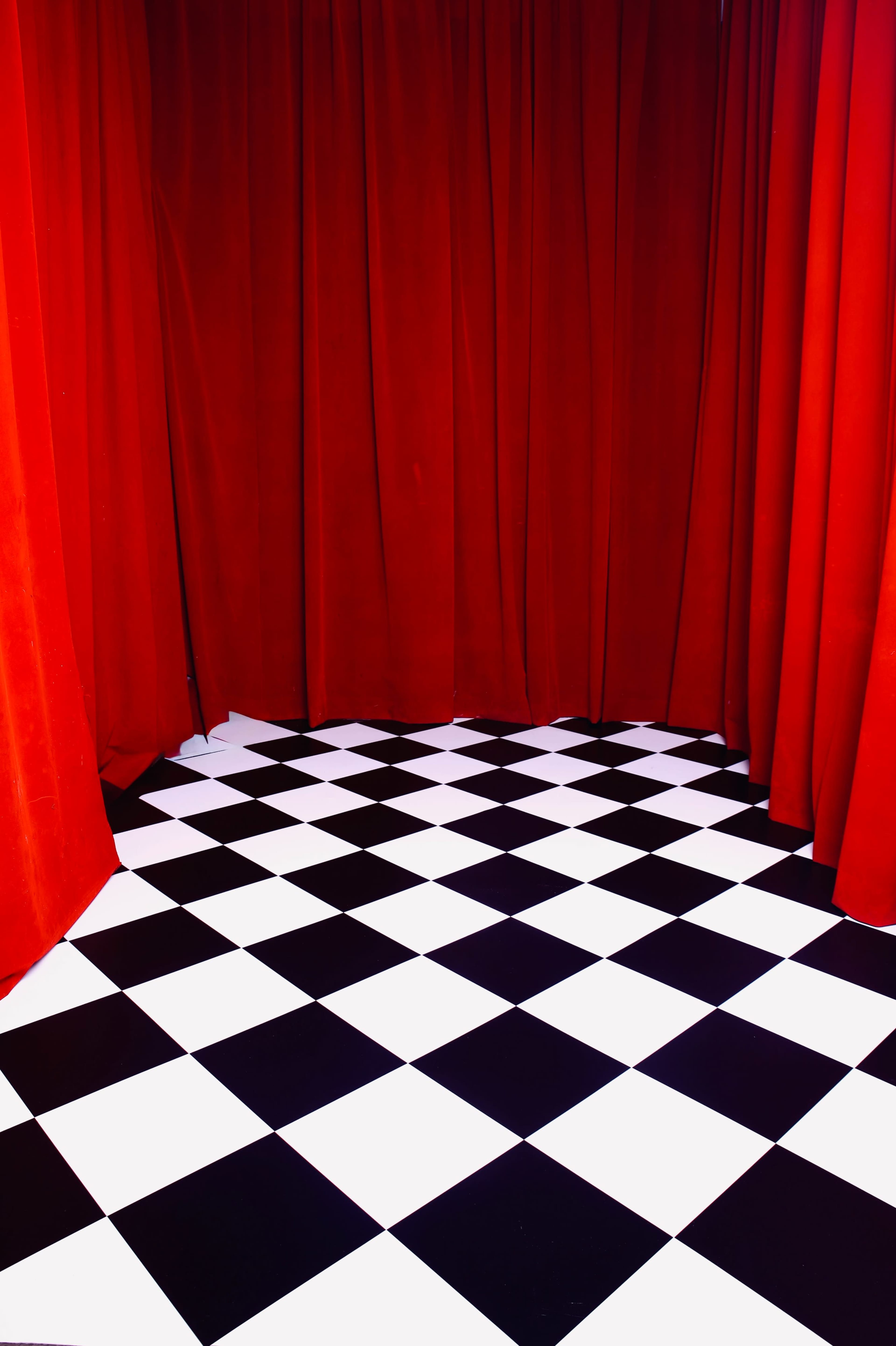 The image shows a stage area with red curtains and a black and white checkered floor.