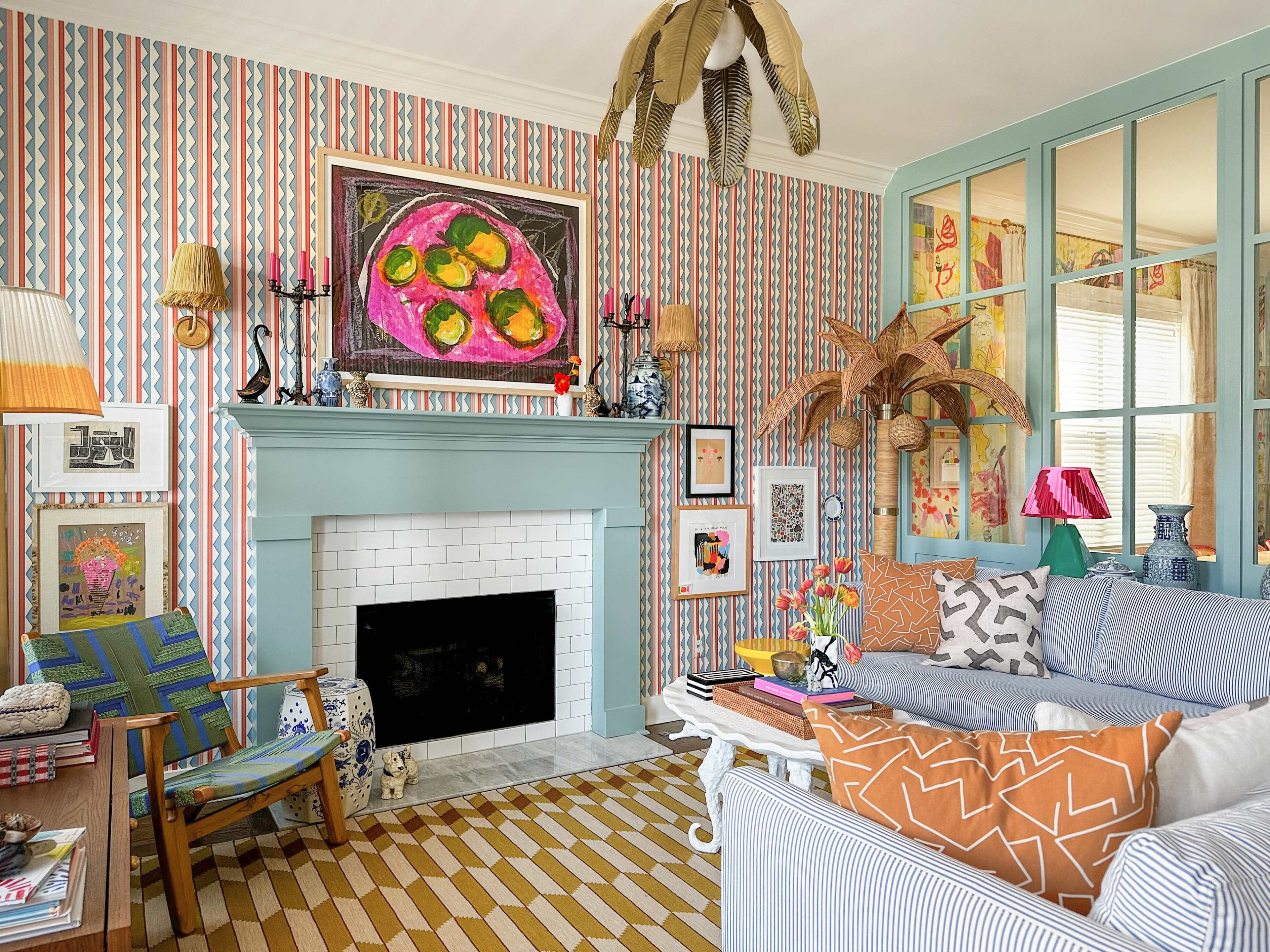 The image showcases a brightly decorated living room featuring colorful wallpaper, a fireplace, and a mix of artistic decor including paintings and patterned furniture.