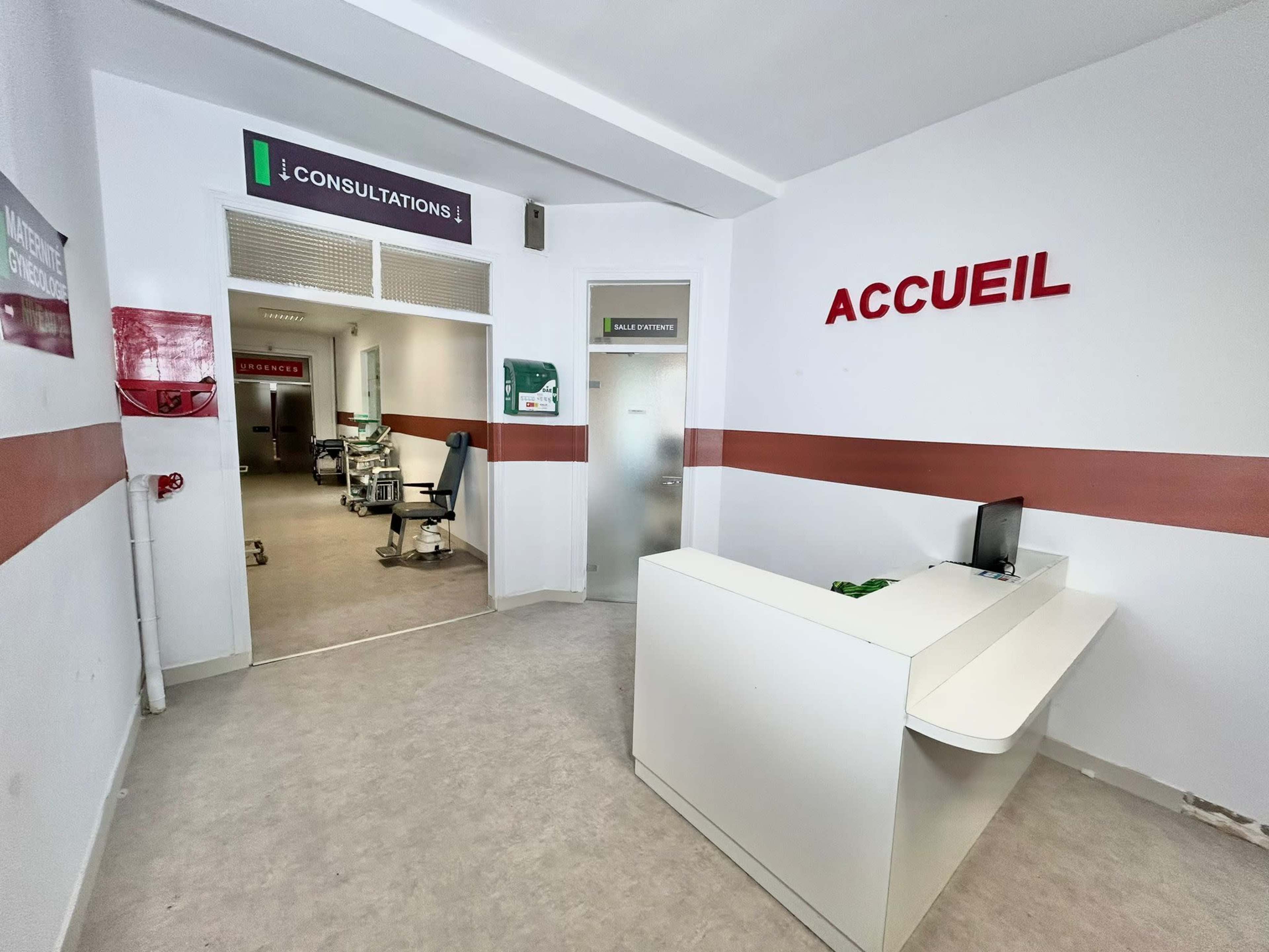 A reception area of a medical facility with a desk and signs indicating consultations and the welcome area.