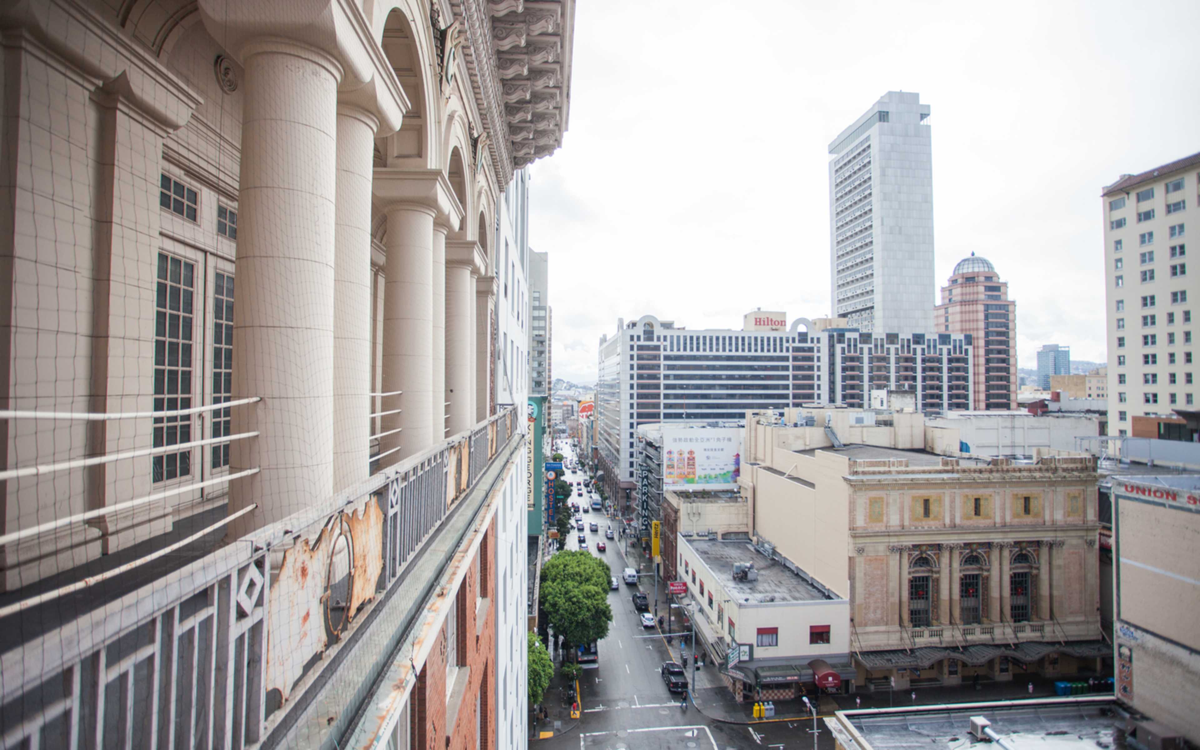 A view of a city street lined with buildings, featuring a mix of architectural styles and a cloudy sky overhead.
