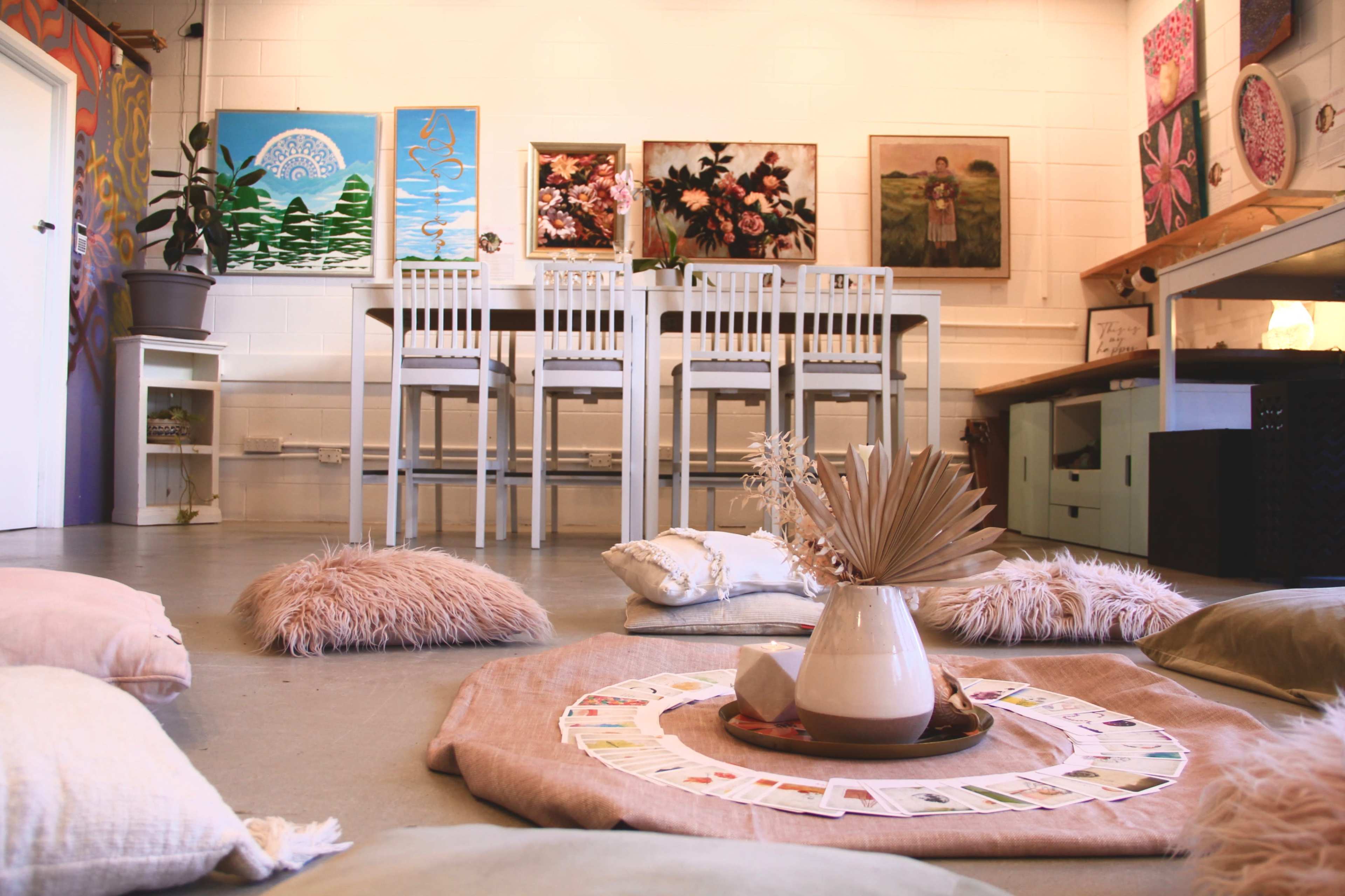 A cozy room with a central seating area of cushions, a table set for dining, and colorful artwork displayed on the walls.