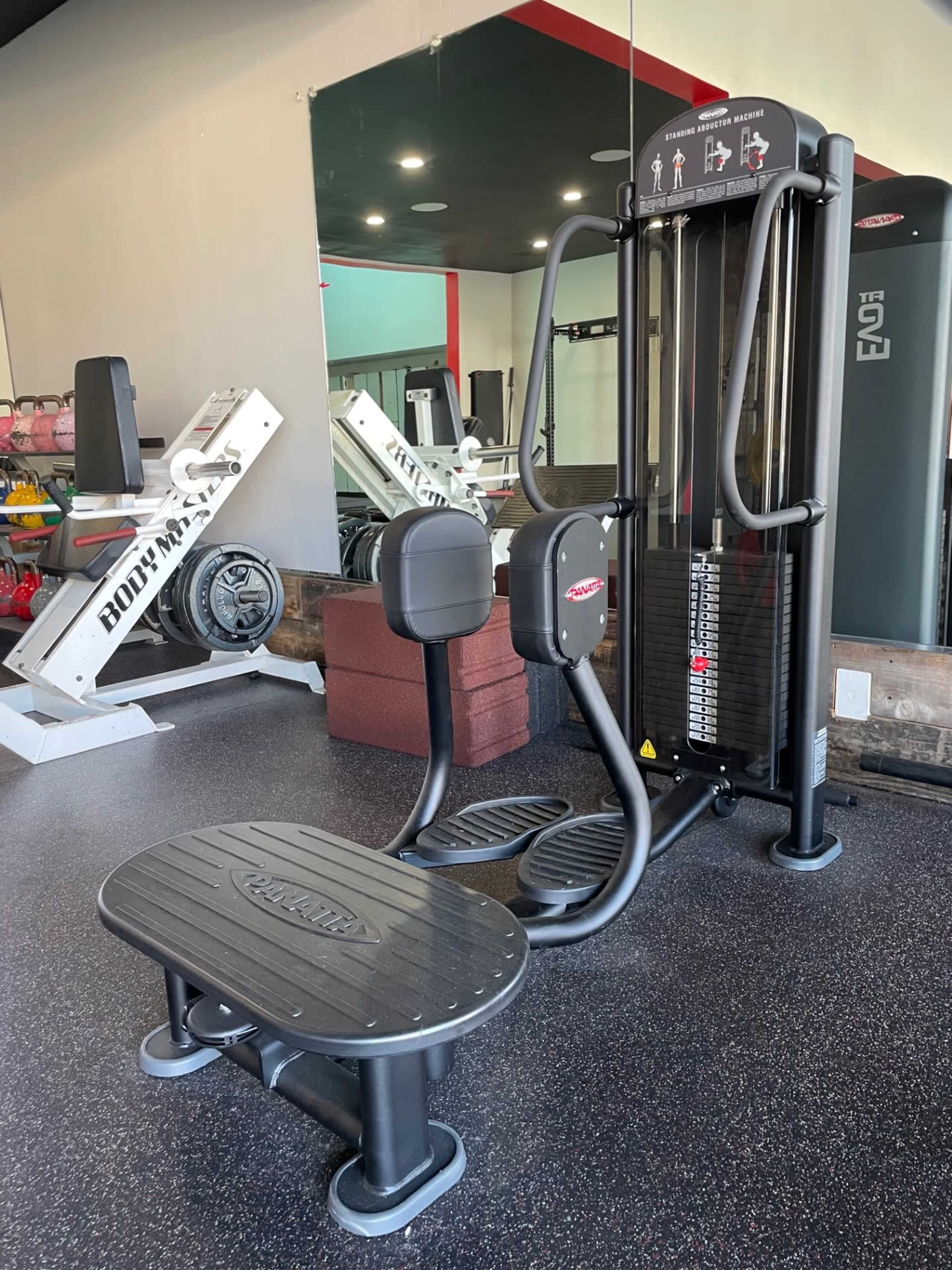 A gym interior featuring a multi-station exercise machine alongside weights and a squat rack.
