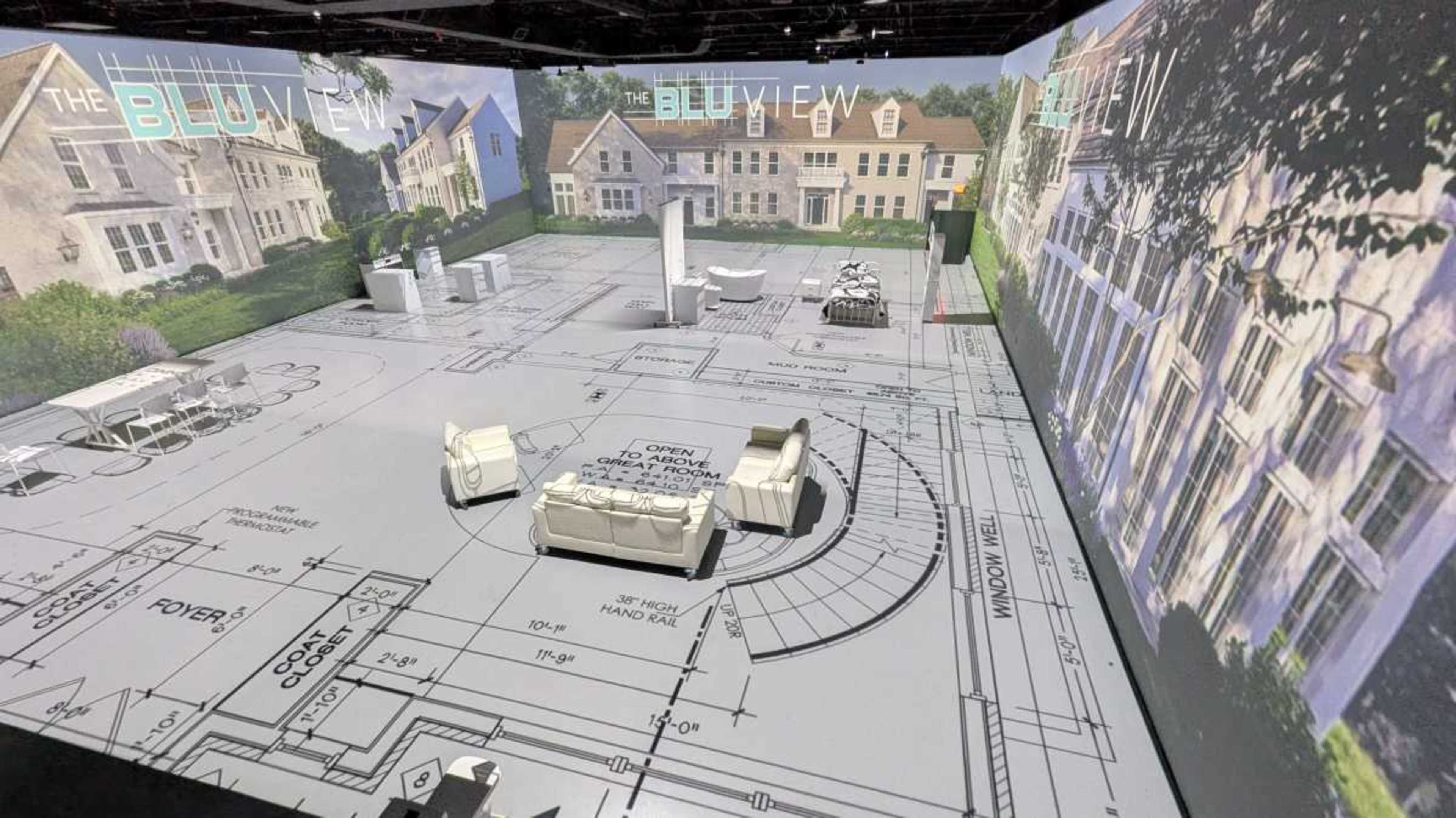 The image shows a spacious interior designed like a blueprint, featuring white furniture and projected architectural designs on the walls and floor.