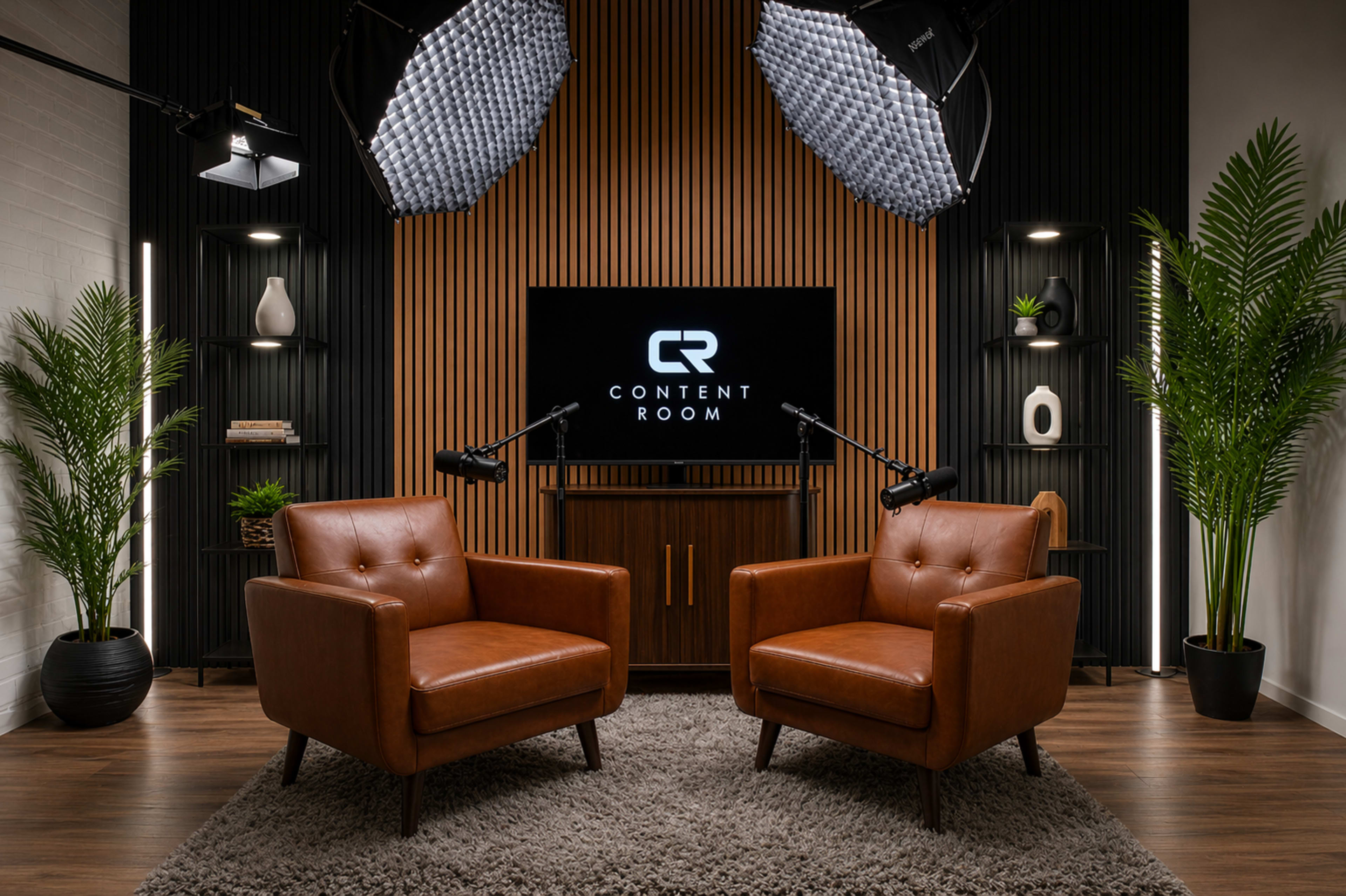 The image features a modern content room with two brown leather chairs facing a central wooden panel wall and a screen displaying the text "CONTENT ROOM."