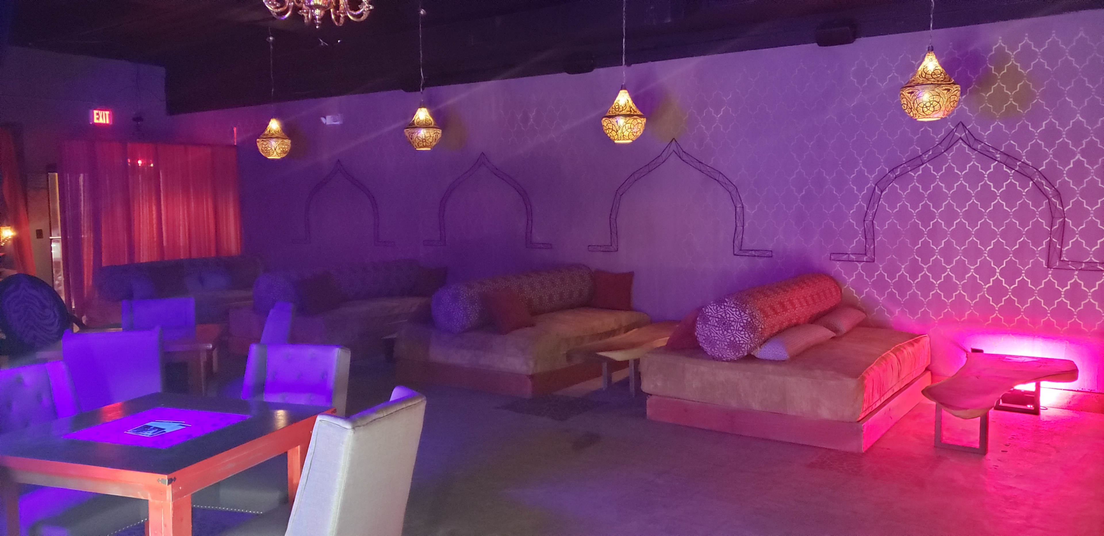 A dimly lit lounge area with plush seating, decorative lamps, and patterned wall designs.