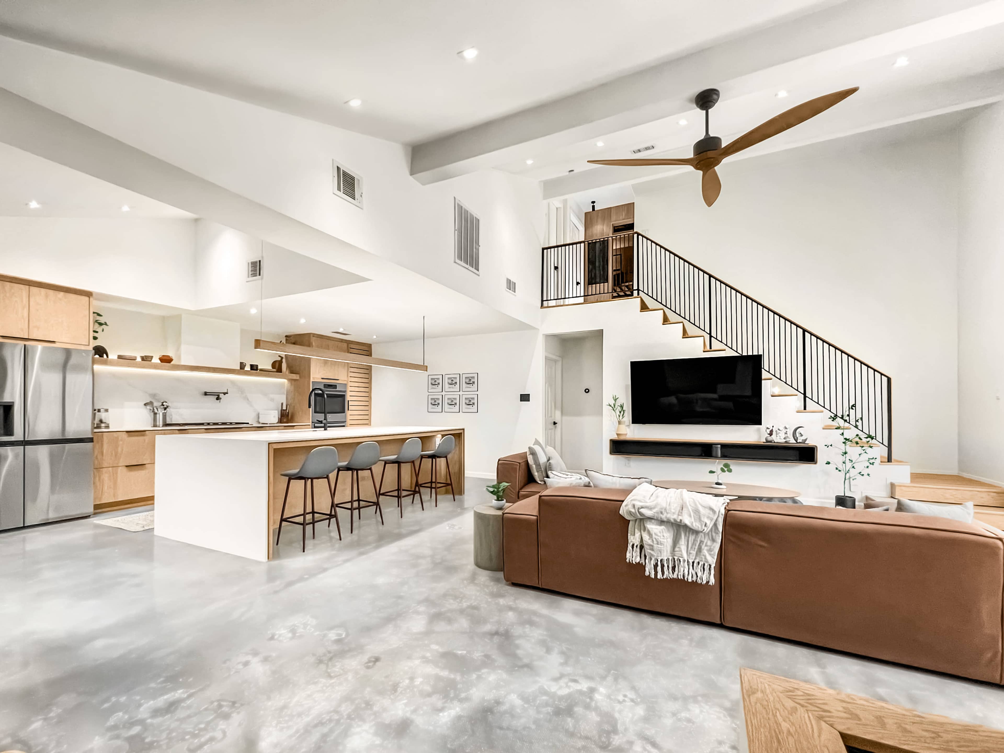A modern, open-concept living space with a kitchen, dining area, and a staircase leading to an upper level.