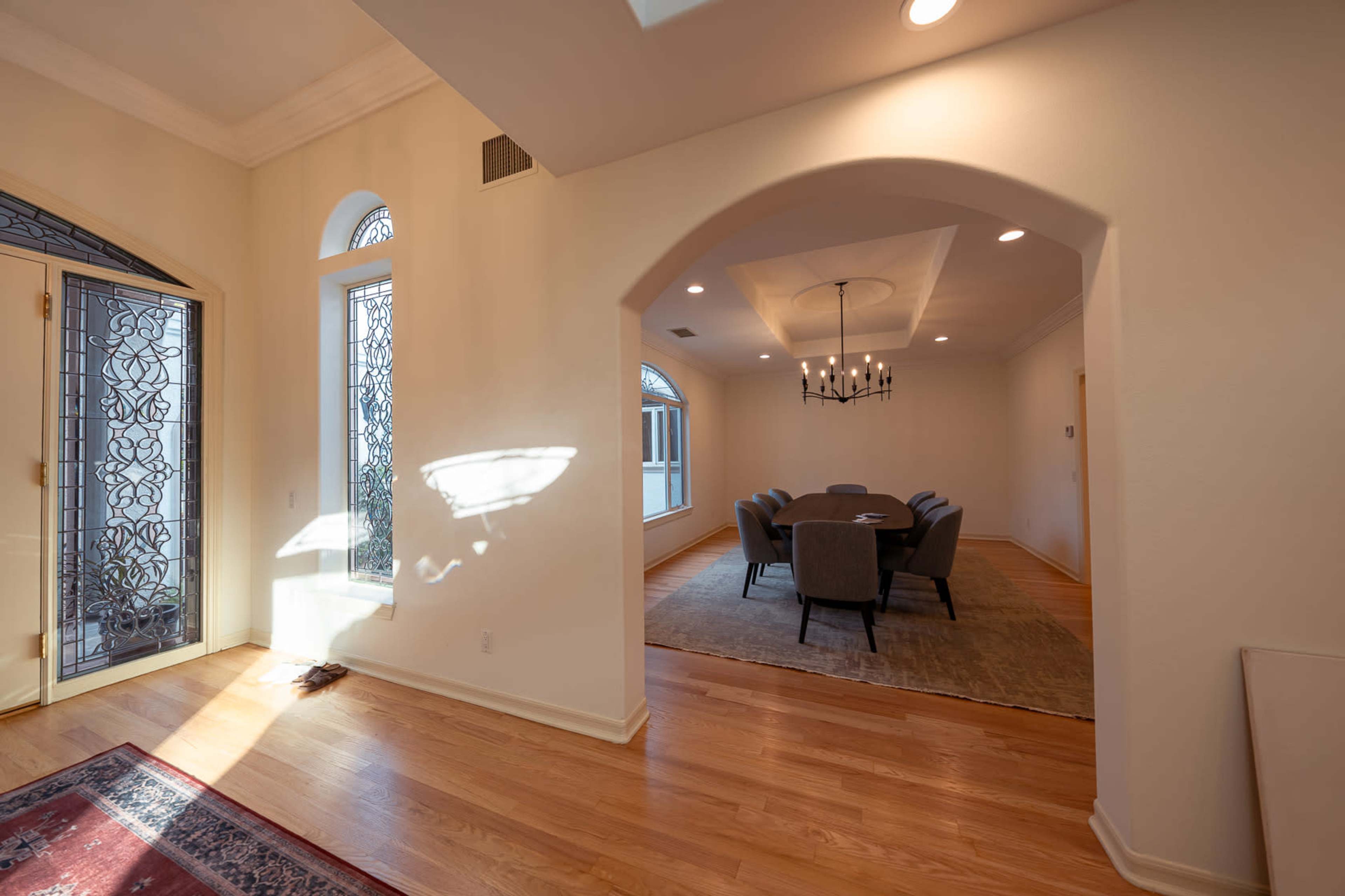 A spacious foyer leads into an elegantly designed dining area, showcasing arched doorways and large windows that allow natural light to fill the space.