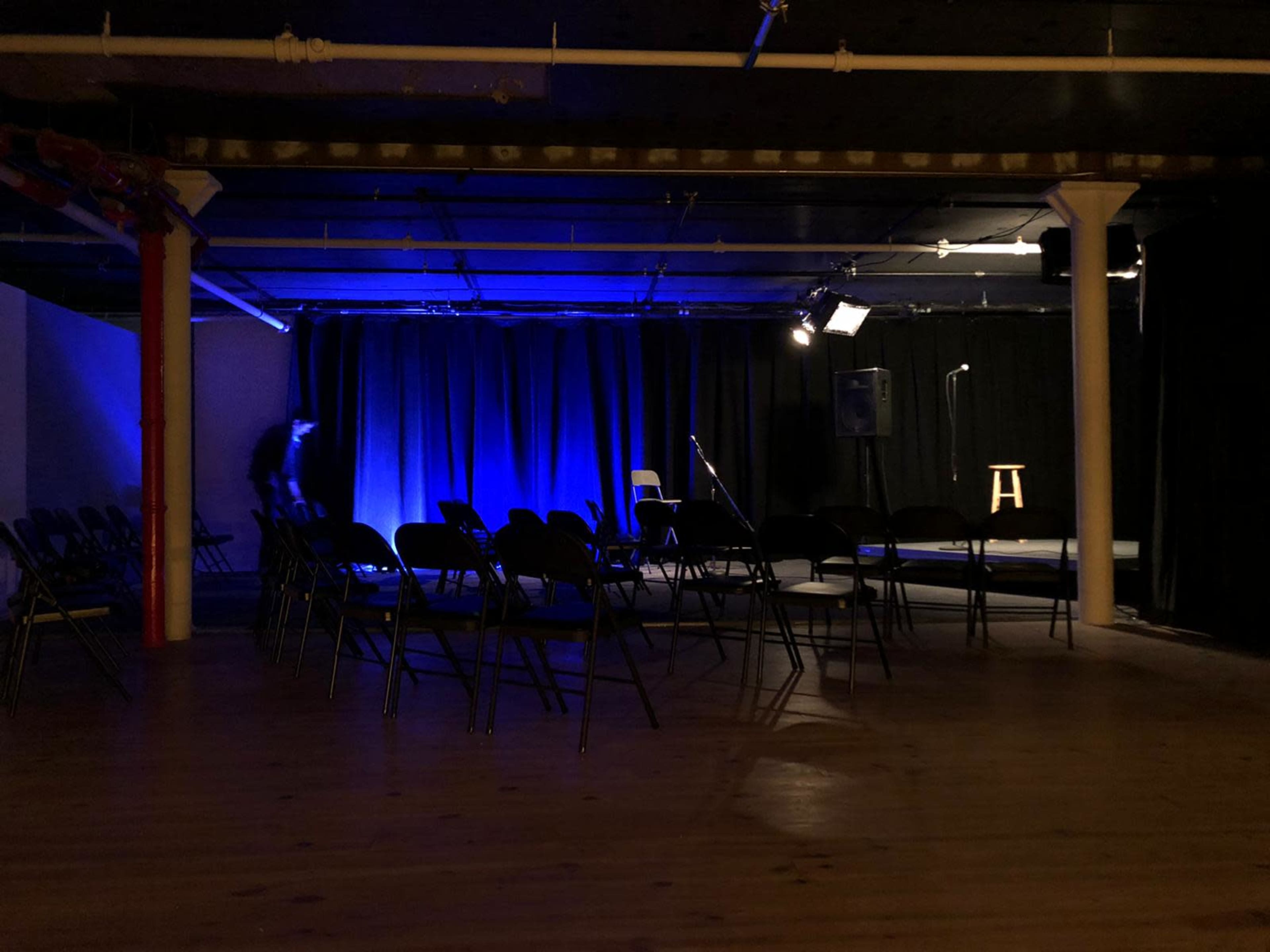 A small performance venue with rows of empty chairs facing a dimly lit stage.