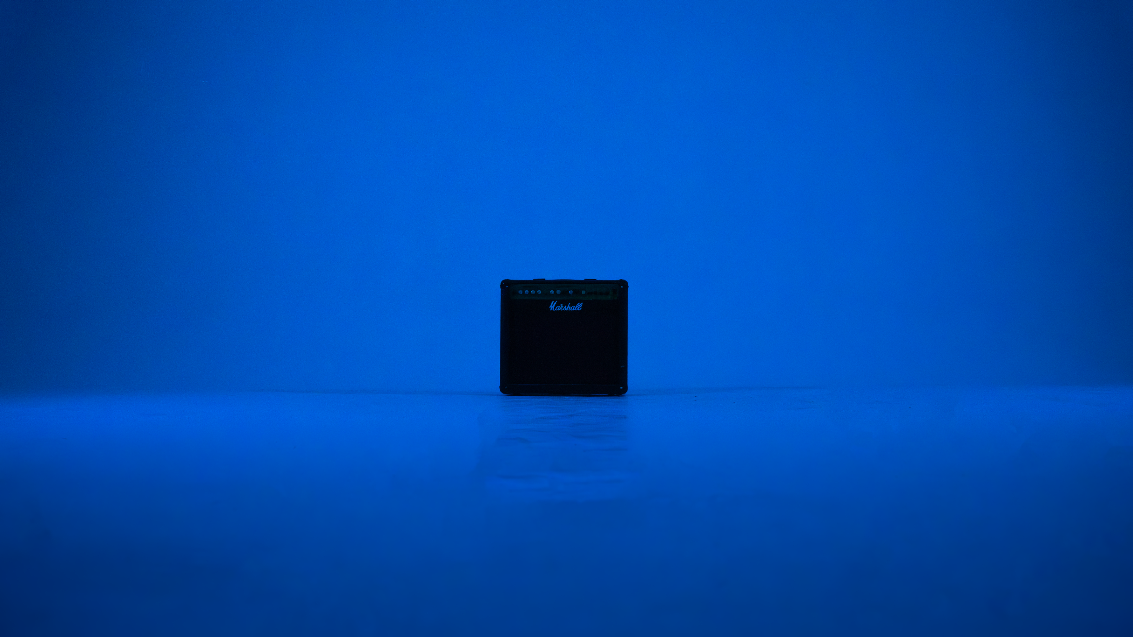 A black guitar amplifier is centered against a solid blue background.