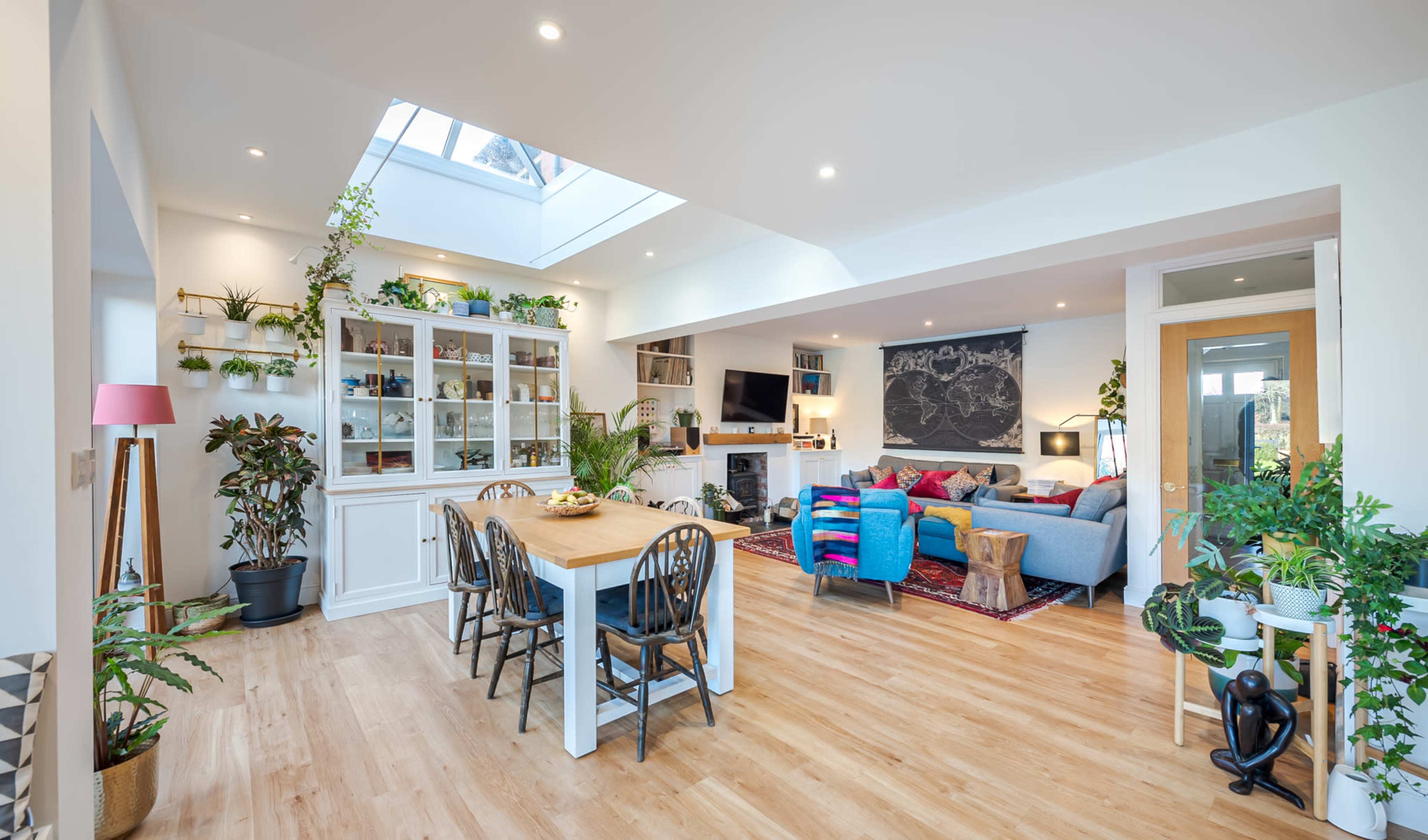A bright, open-plan living and dining area adorned with various potted plants and modern furnishings.