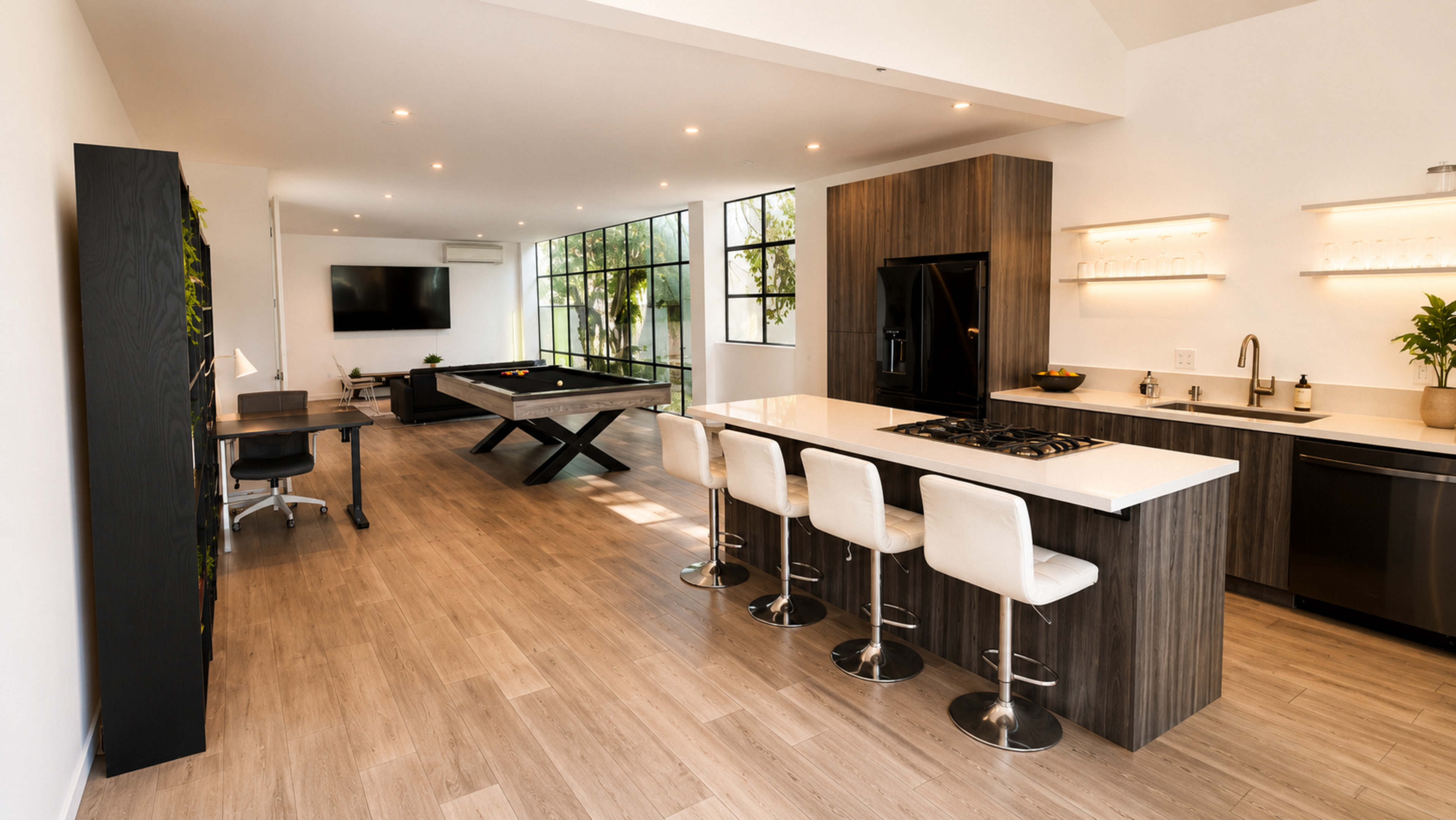The image shows a modern open-concept kitchen and living area, featuring a sleek kitchen island with bar stools, a pool table, and large windows that allow natural light to fill the space.