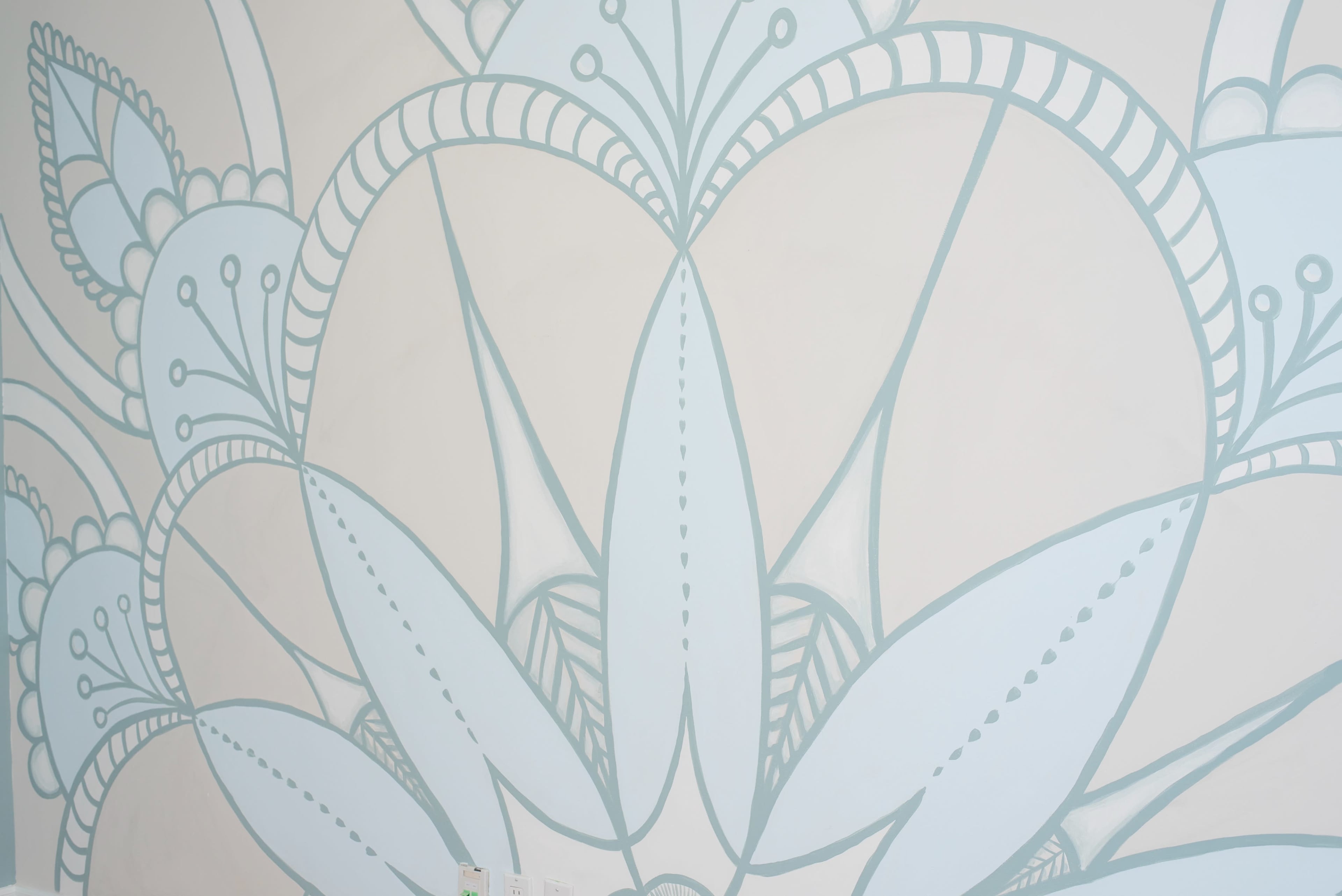The image shows a large, blue botanical mural painted on a white wall.