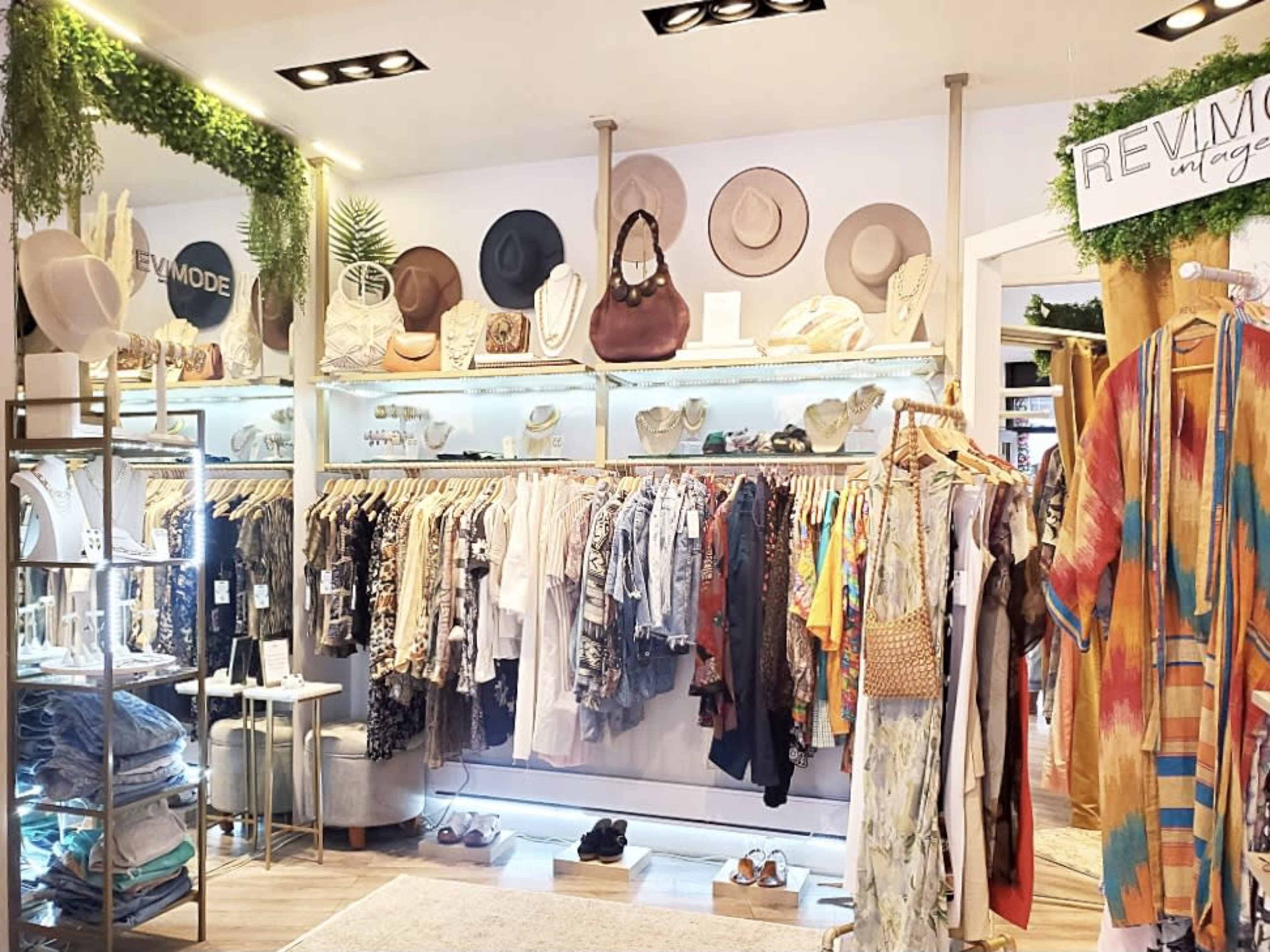 A boutique interior with clothing racks, hats displayed on the wall, and various accessories on shelves.