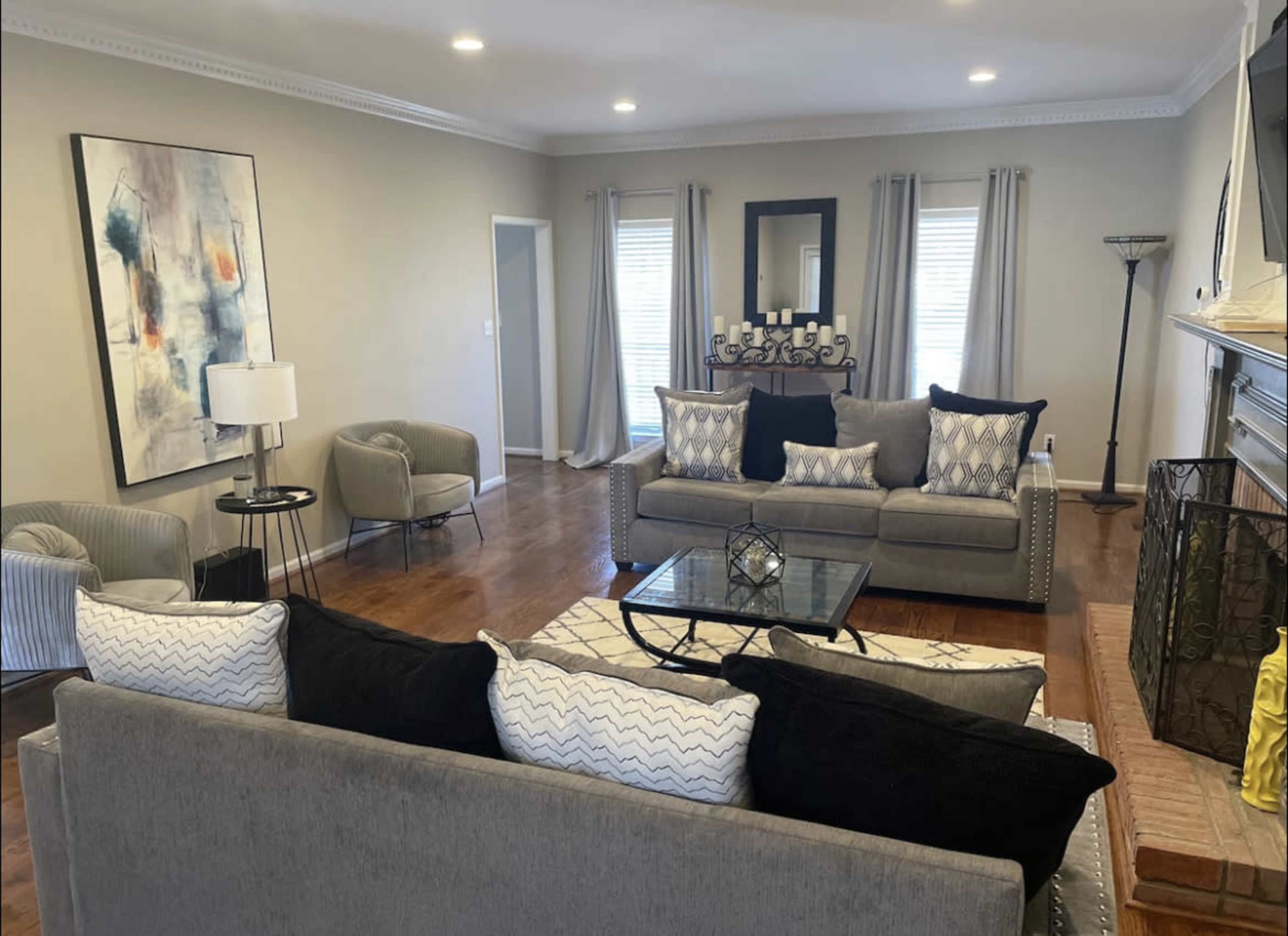 The living room features two sofas, a coffee table, and decorative accents, with natural light coming through the windows.