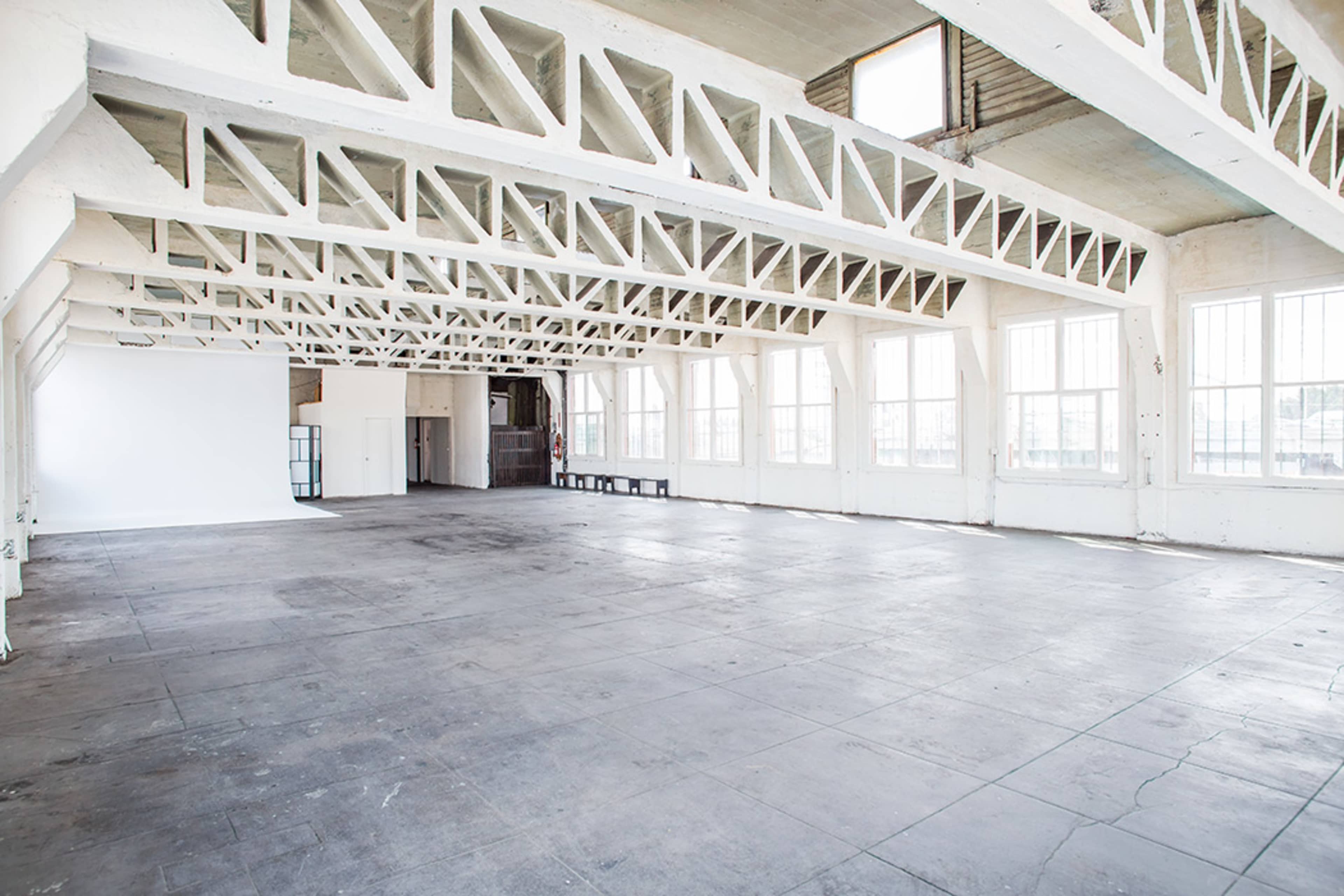 A spacious, empty room with high ceilings and large windows.