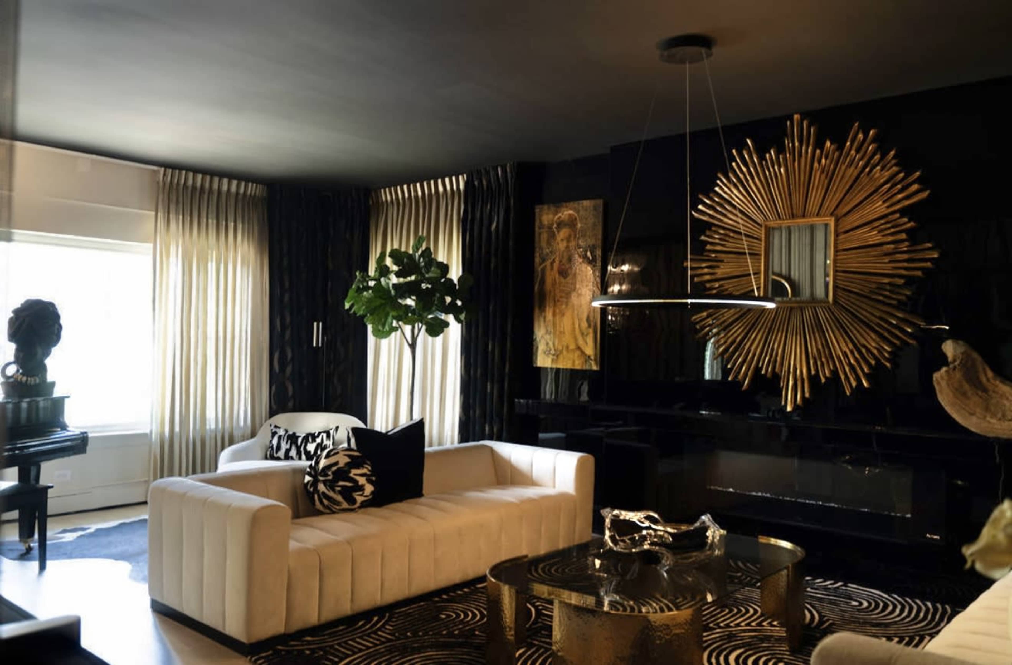 The image shows a stylish living room featuring a white velvet sofa, a round coffee table, a large decorative mirror, and floor-to-ceiling curtains.