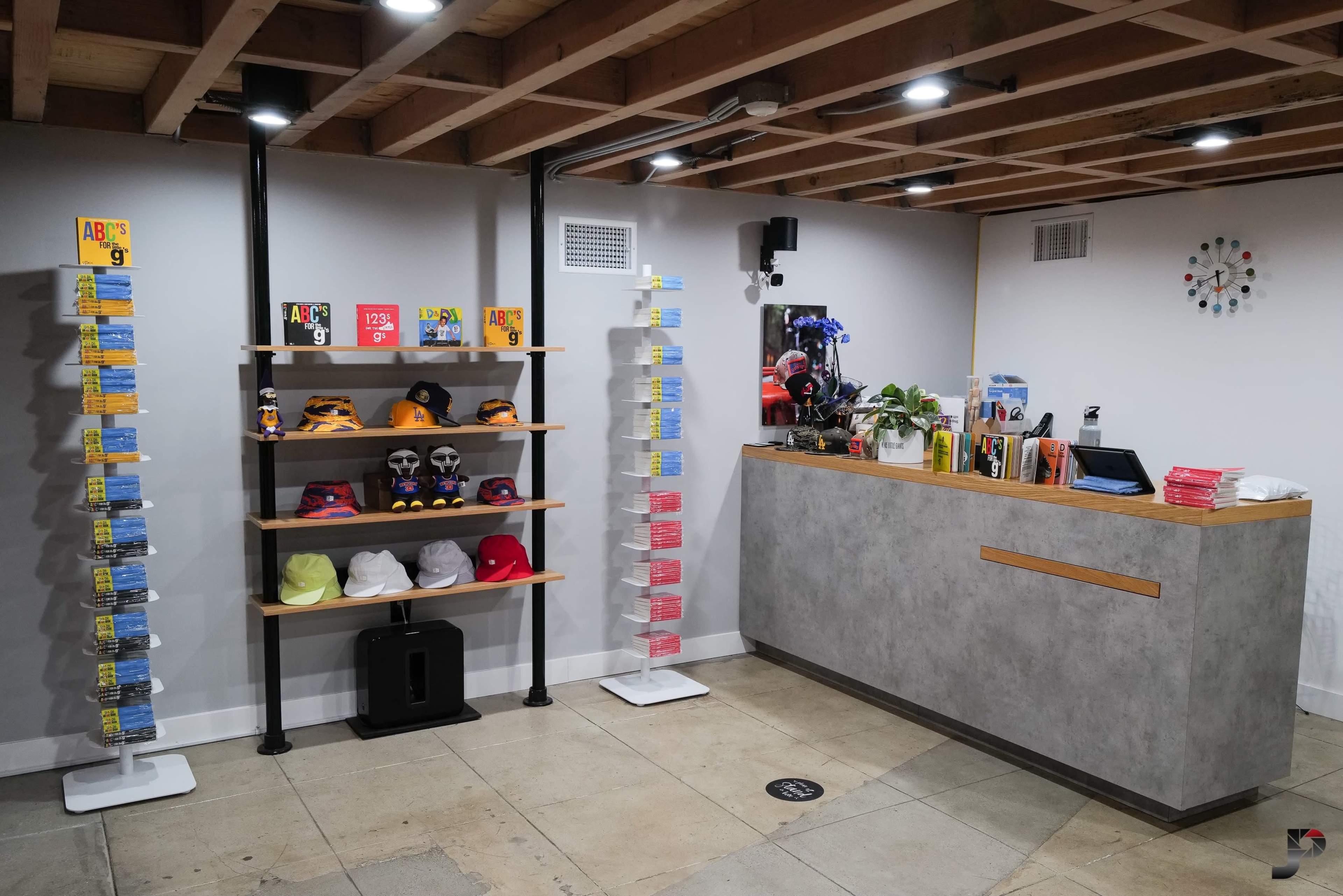 A retail space with shelves displaying hats and merchandise, a reception counter, and a wall clock.