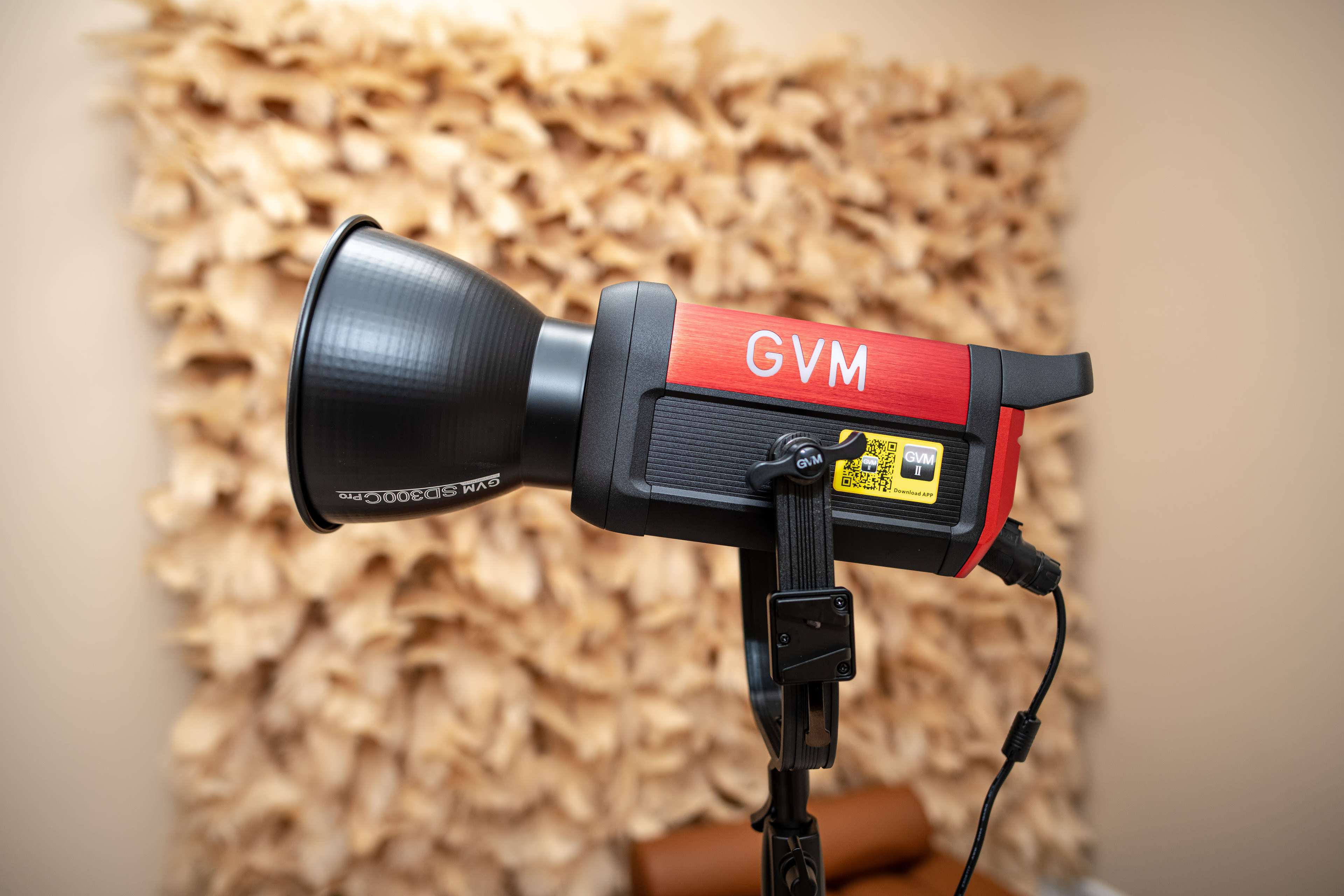 A GVM studio light is mounted on a tripod in front of a textured wall.