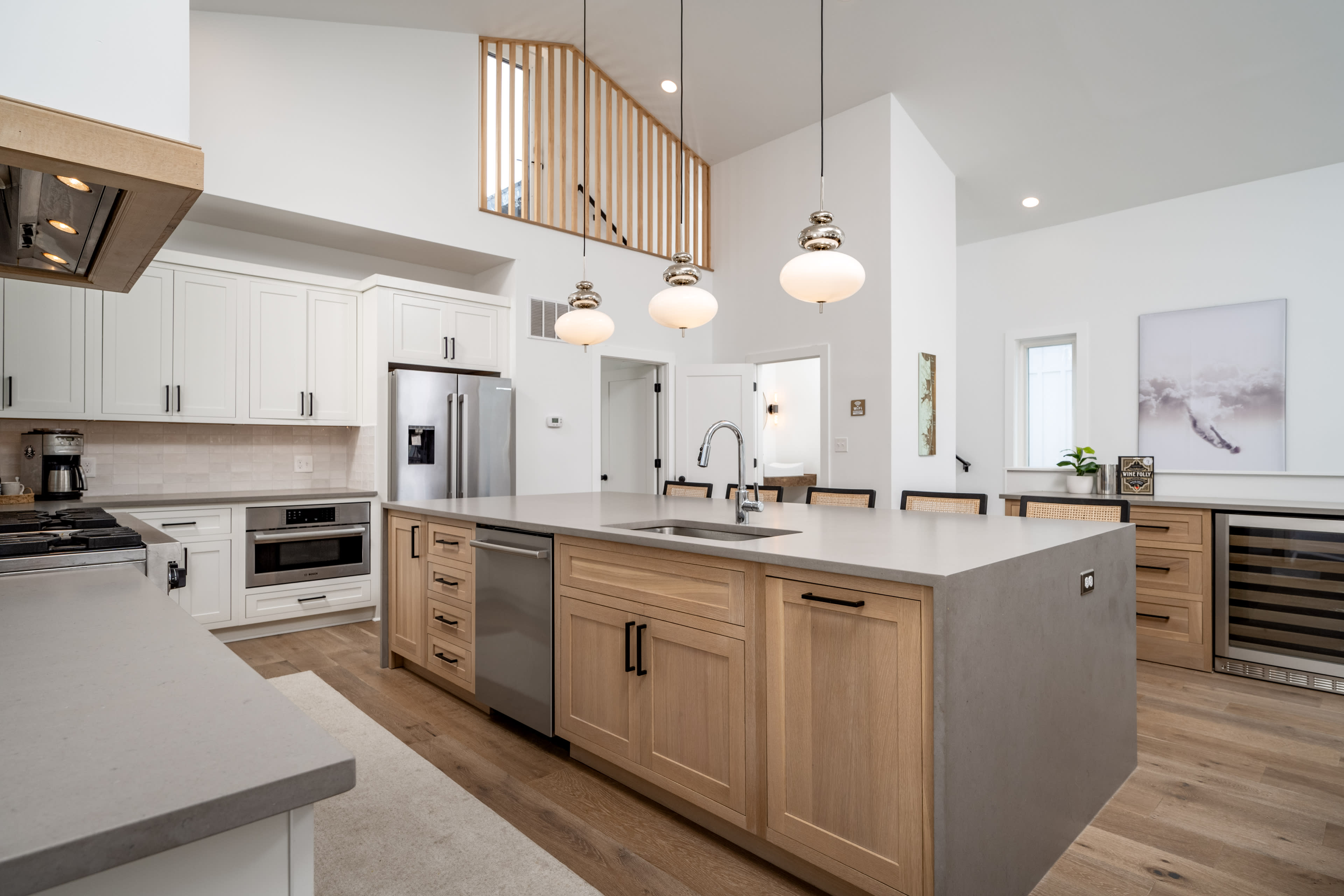 The kitchen features a central island with a light gray countertop, wooden cabinetry, stainless steel appliances, and pendant lighting above the island.