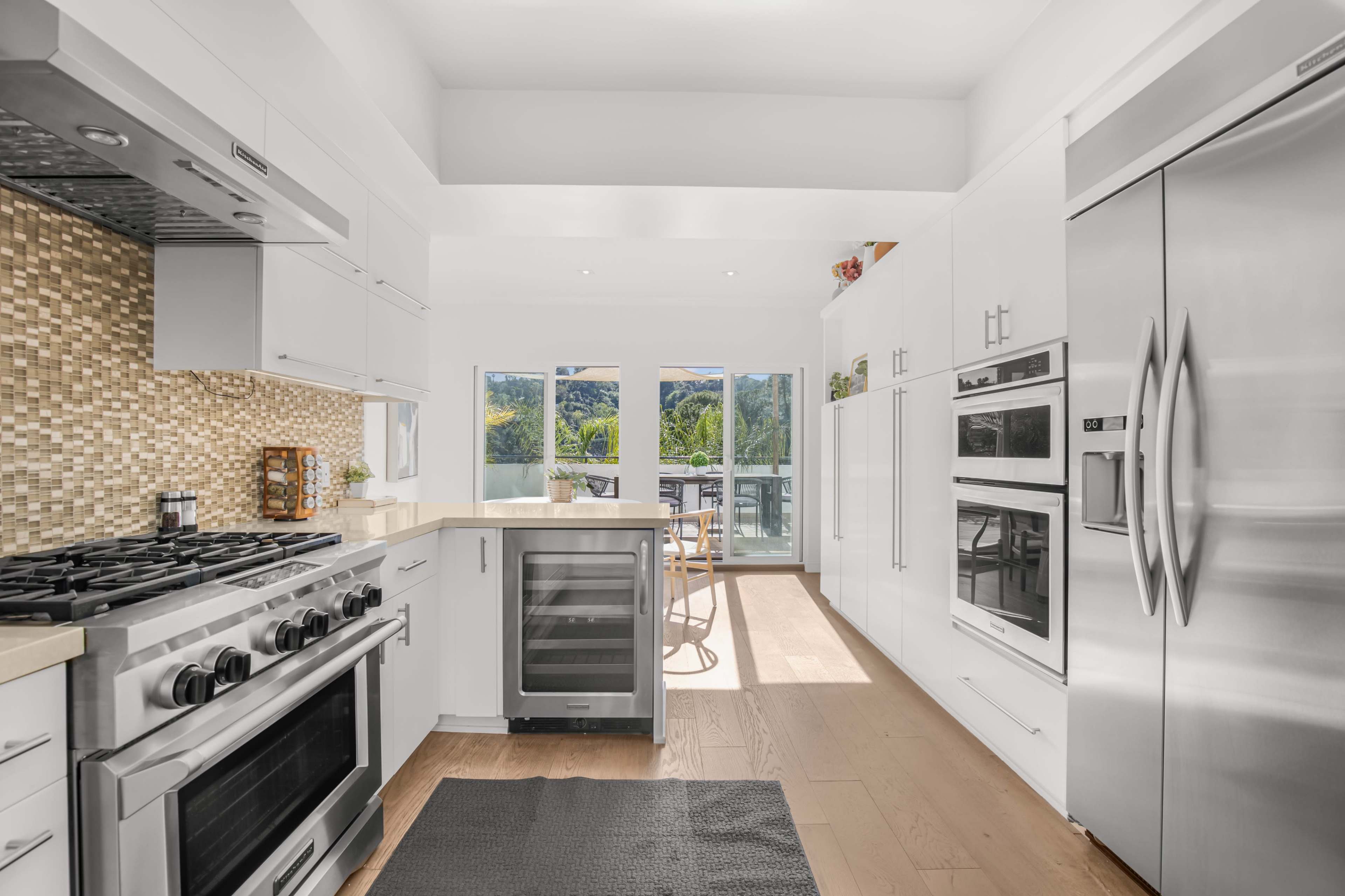 A modern kitchen features stainless steel appliances, a spacious island, and large windows that overlook a scenic outdoor view.