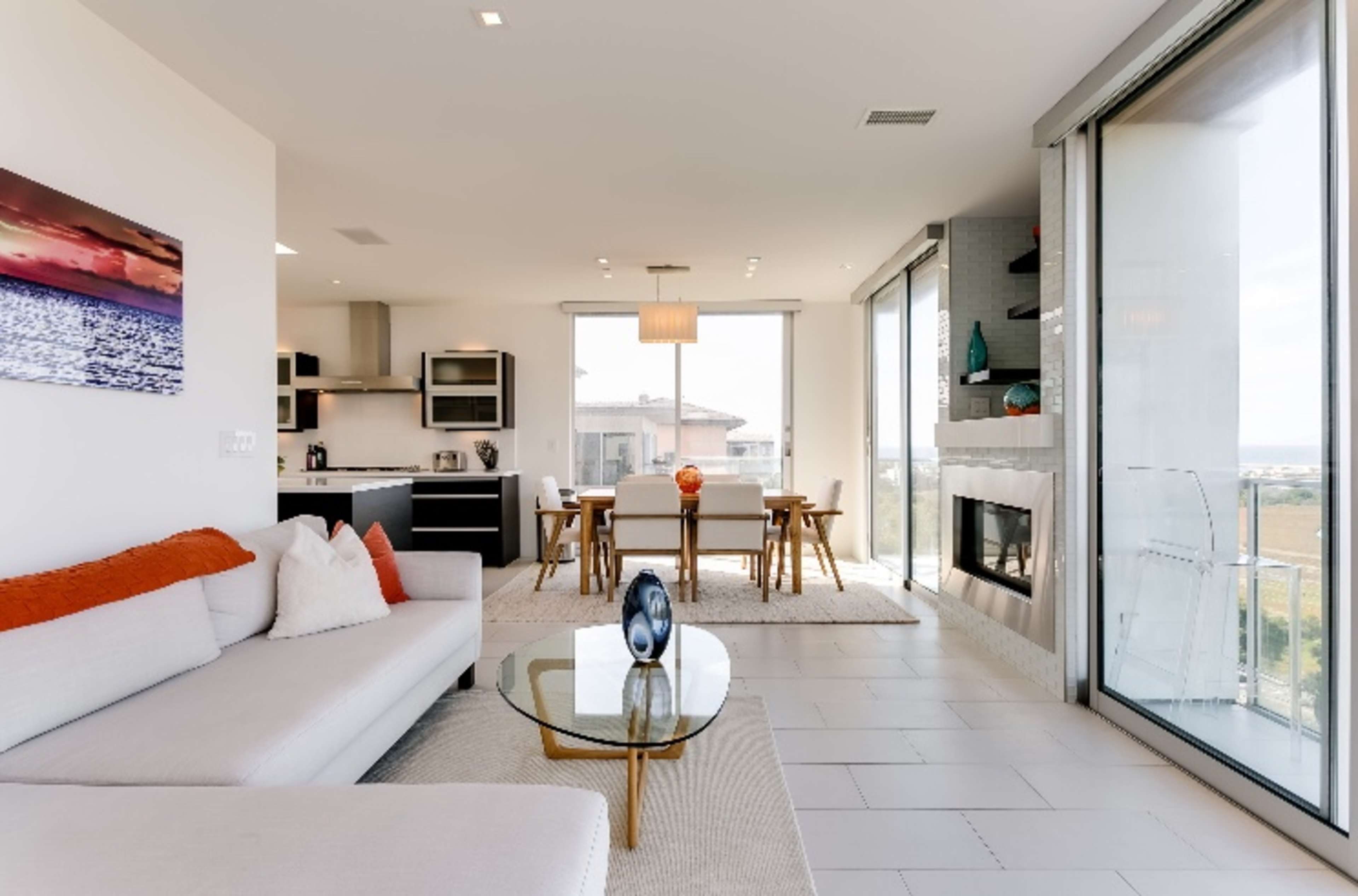 A modern, open-concept living space with a sectional sofa, dining area, and large windows overlooking a landscape.