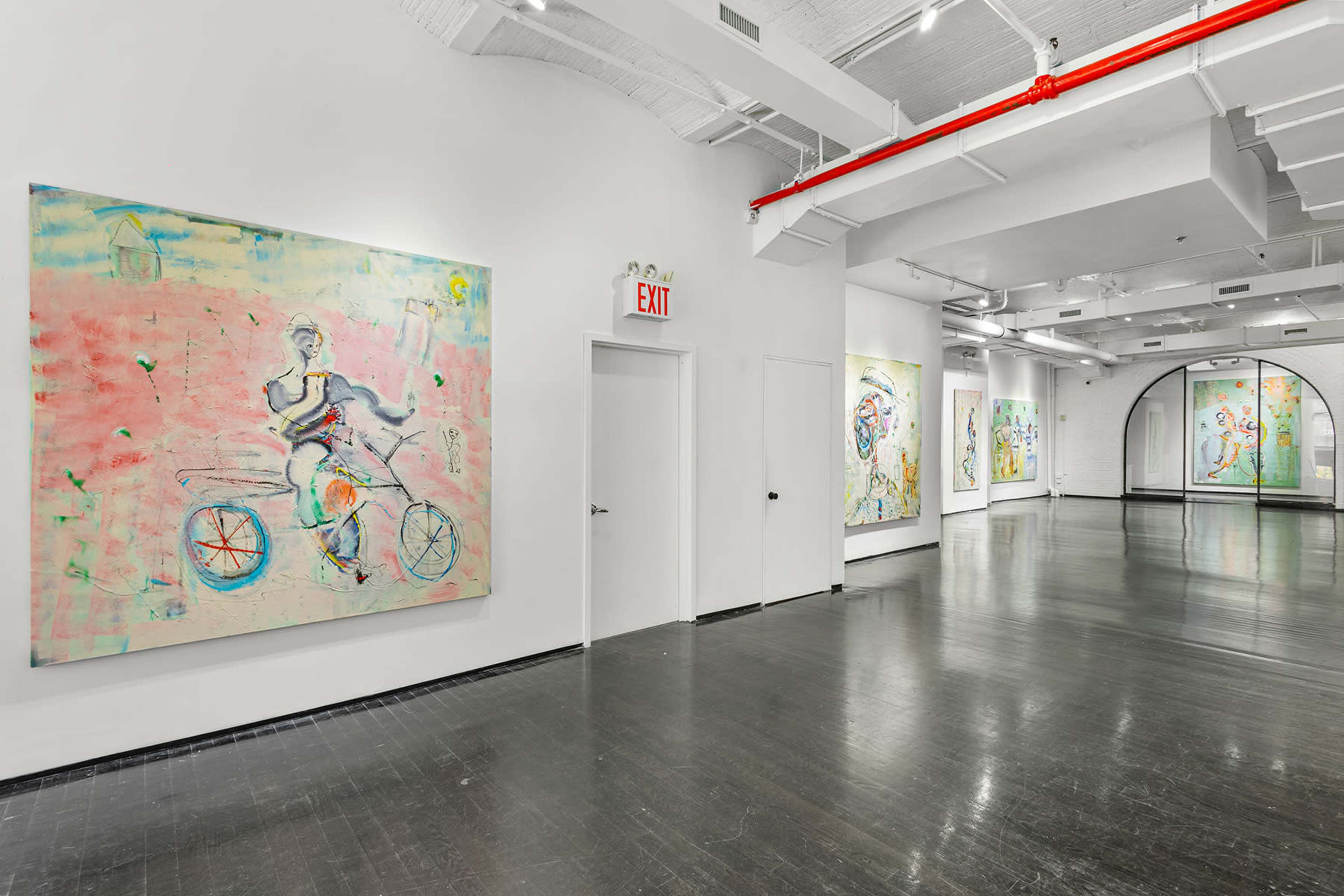 A spacious art gallery with multiple paintings on the white walls and a dark floor, leading towards an exit sign and an arched doorway.
