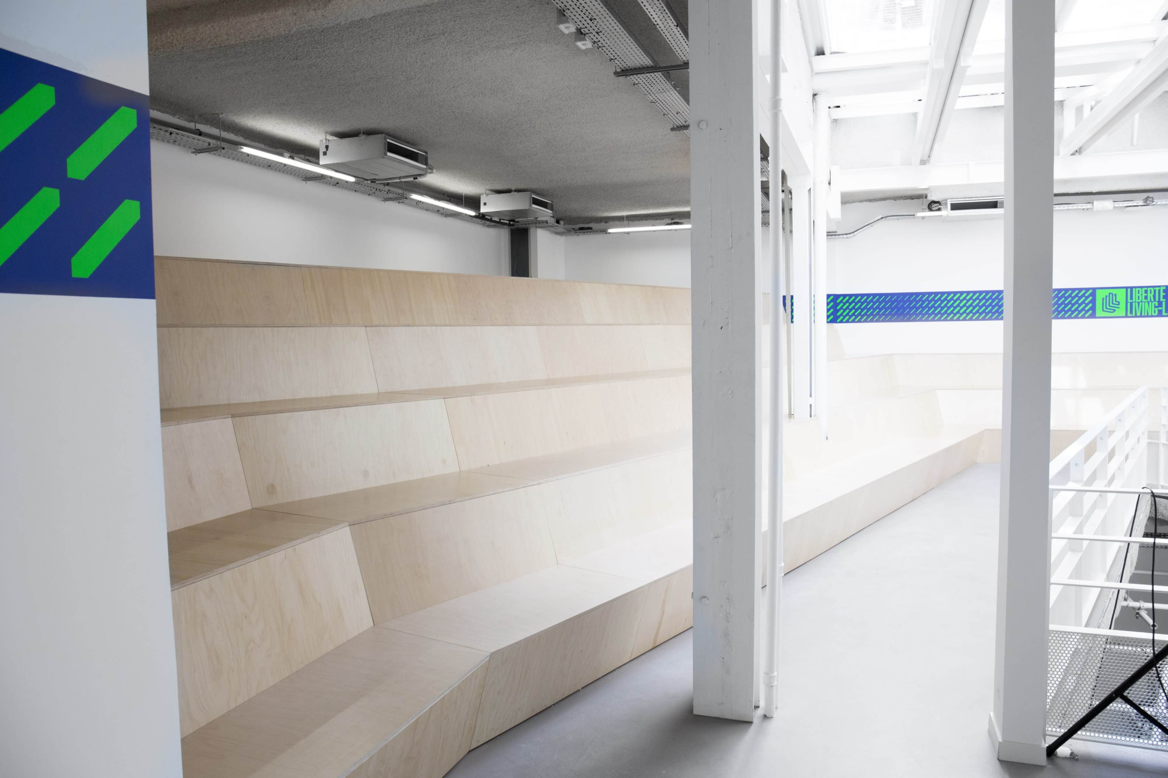 A spacious interior featuring tiered wooden seating and white walls with colorful accents.