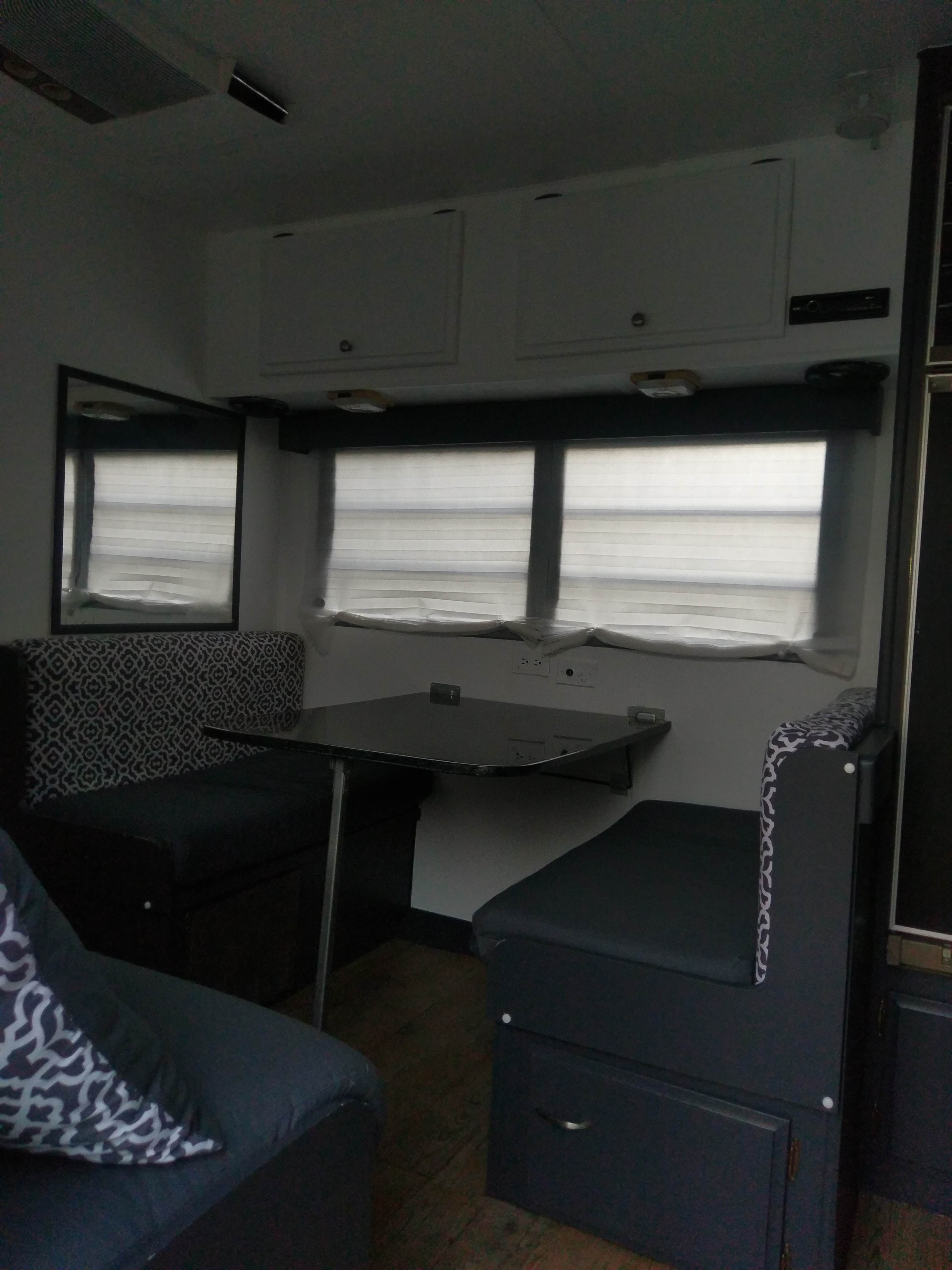 A compact interior of a camper van with a small dining area and seating.