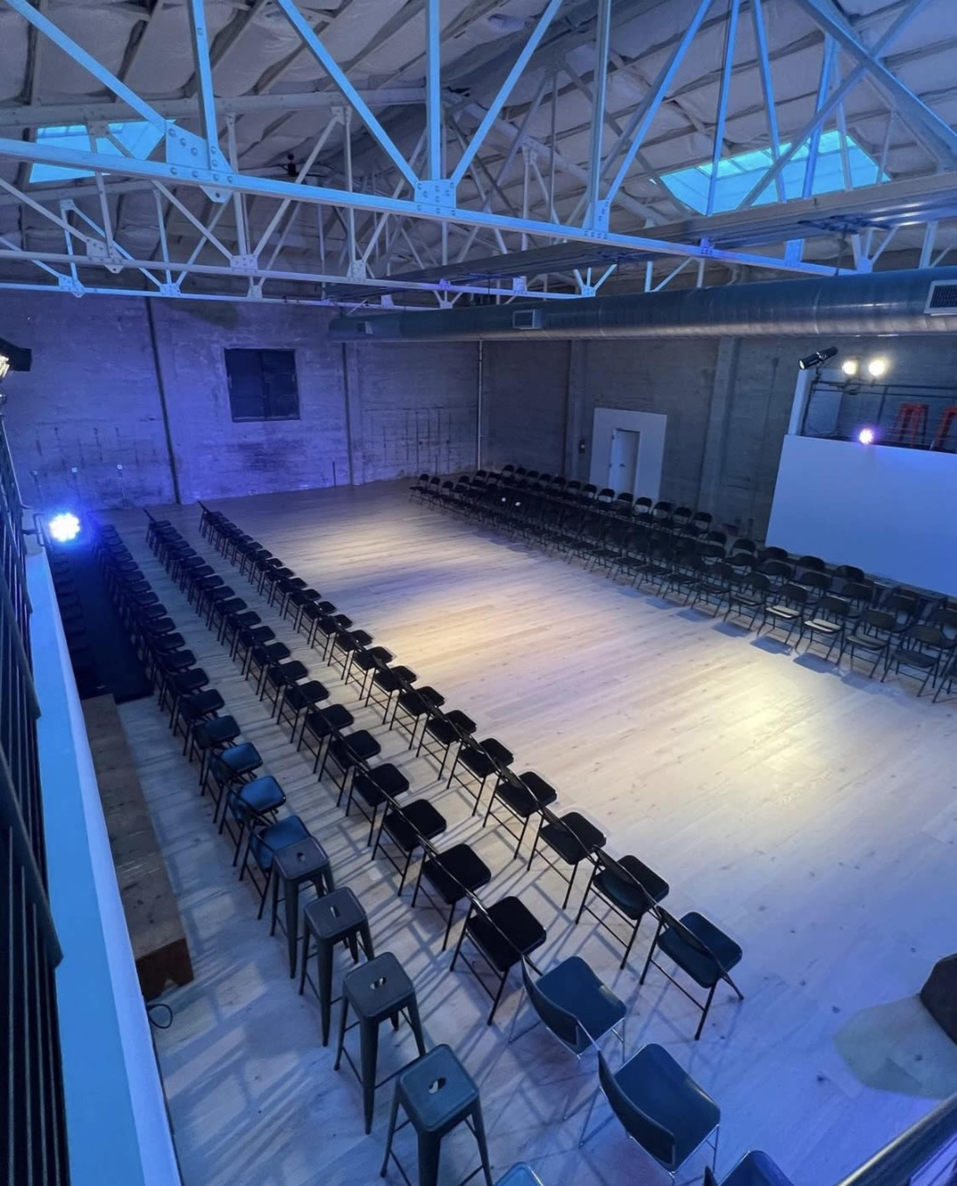 An empty auditorium with rows of black chairs arranged neatly facing a blank screen.