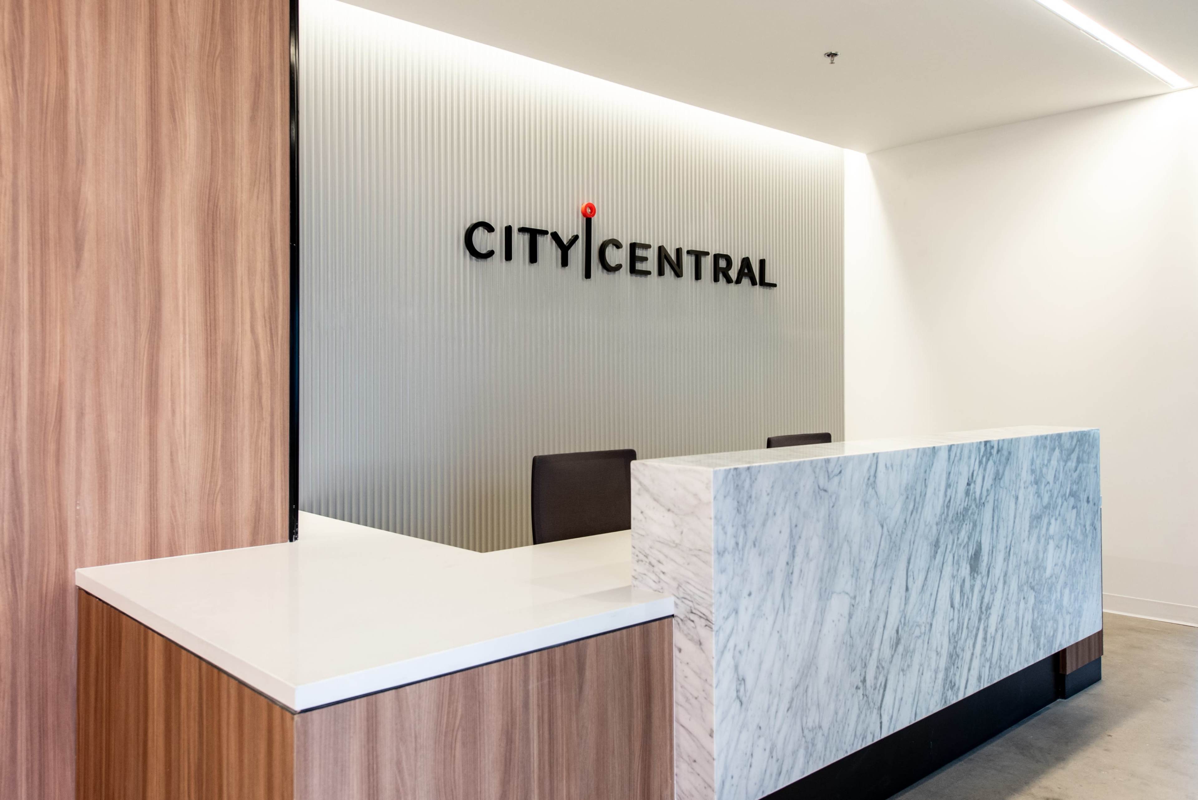 A modern reception area with a marble front desk and a wall displaying the text "CITY CENTRAL."