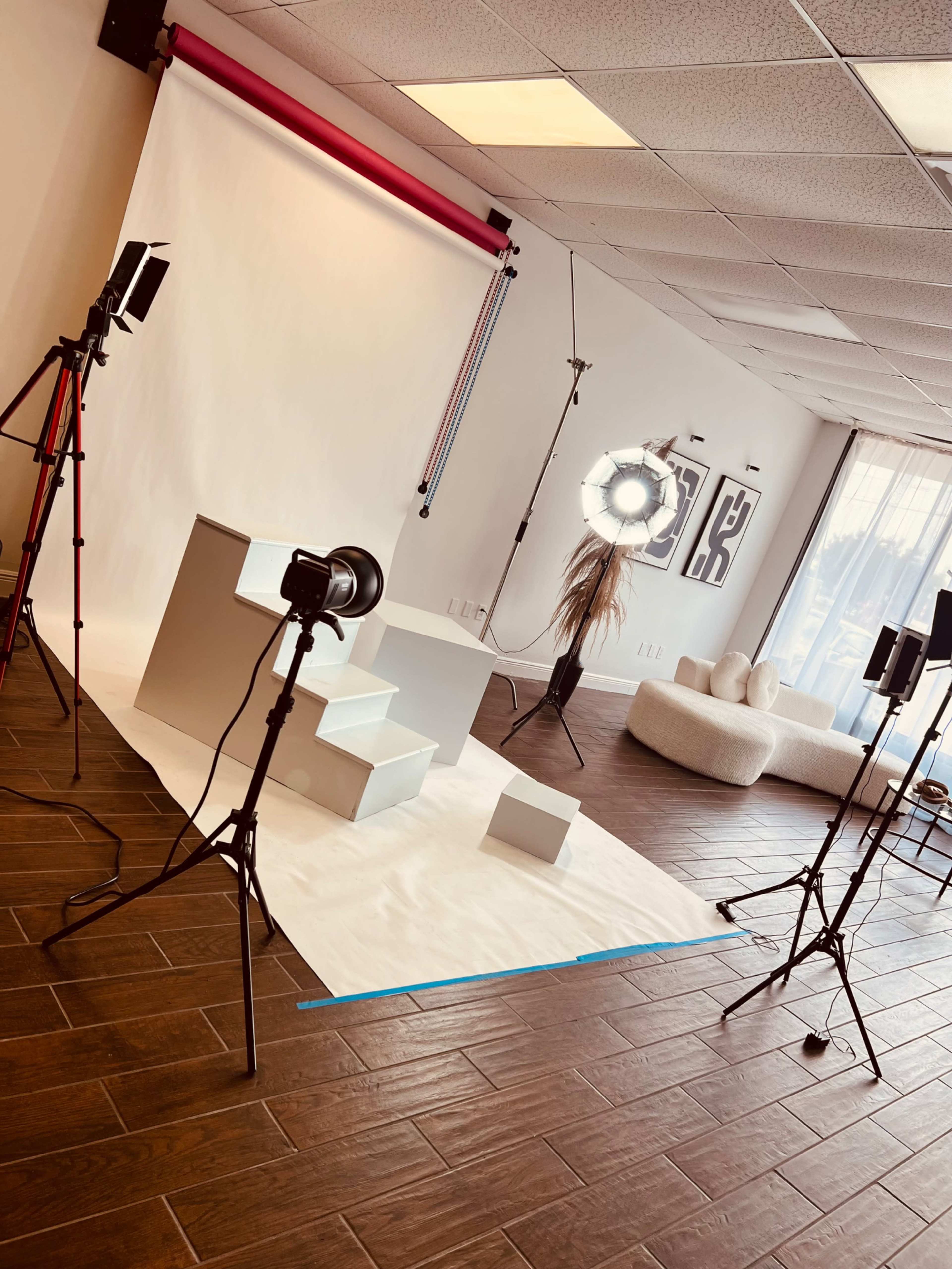 The image shows a photography studio with a backdrop, lighting equipment, and props arranged on a white surface.