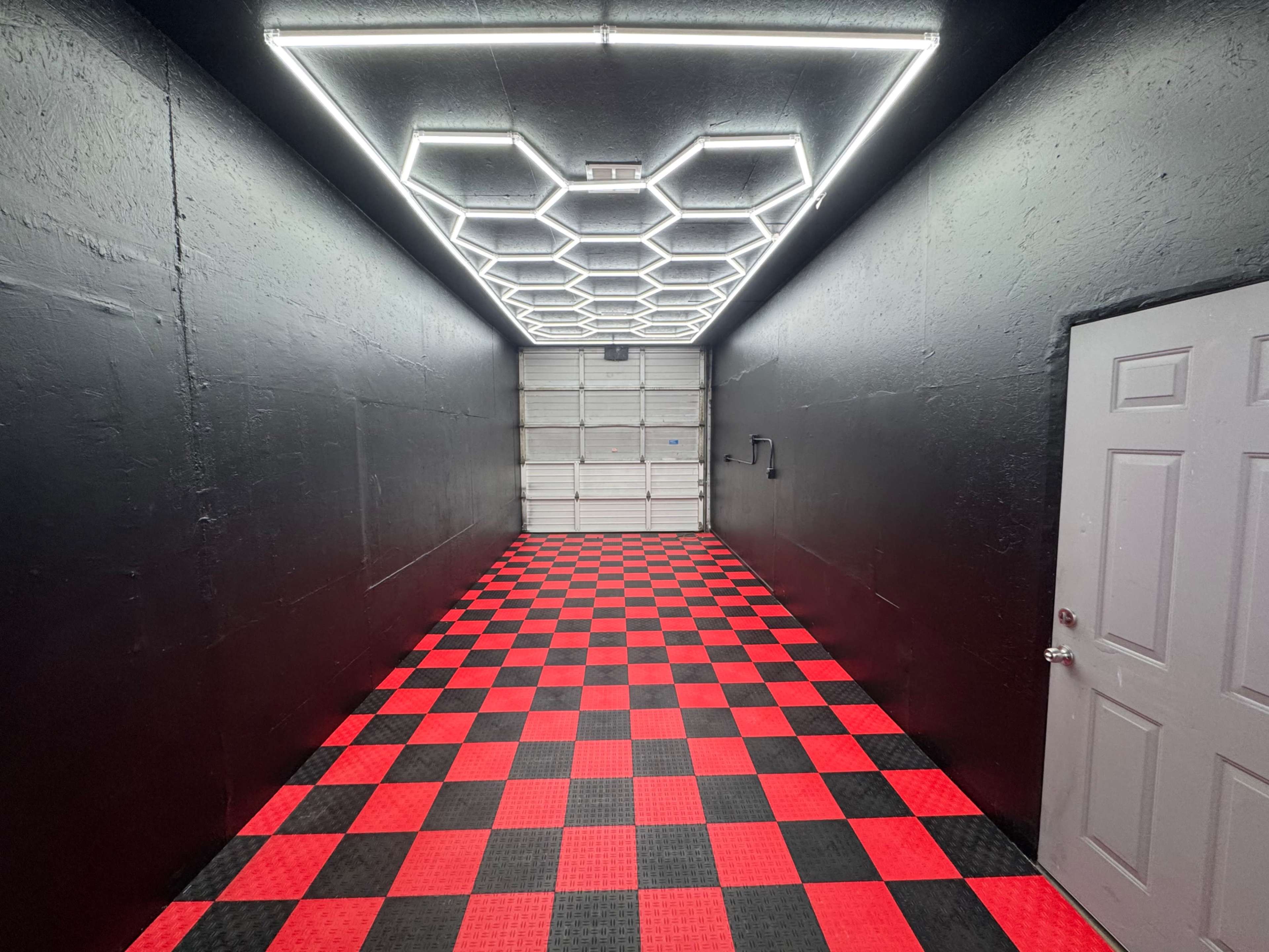 The image shows a long, narrow corridor with a black and red checkered floor and a ceiling featuring hexagonal LED lights.