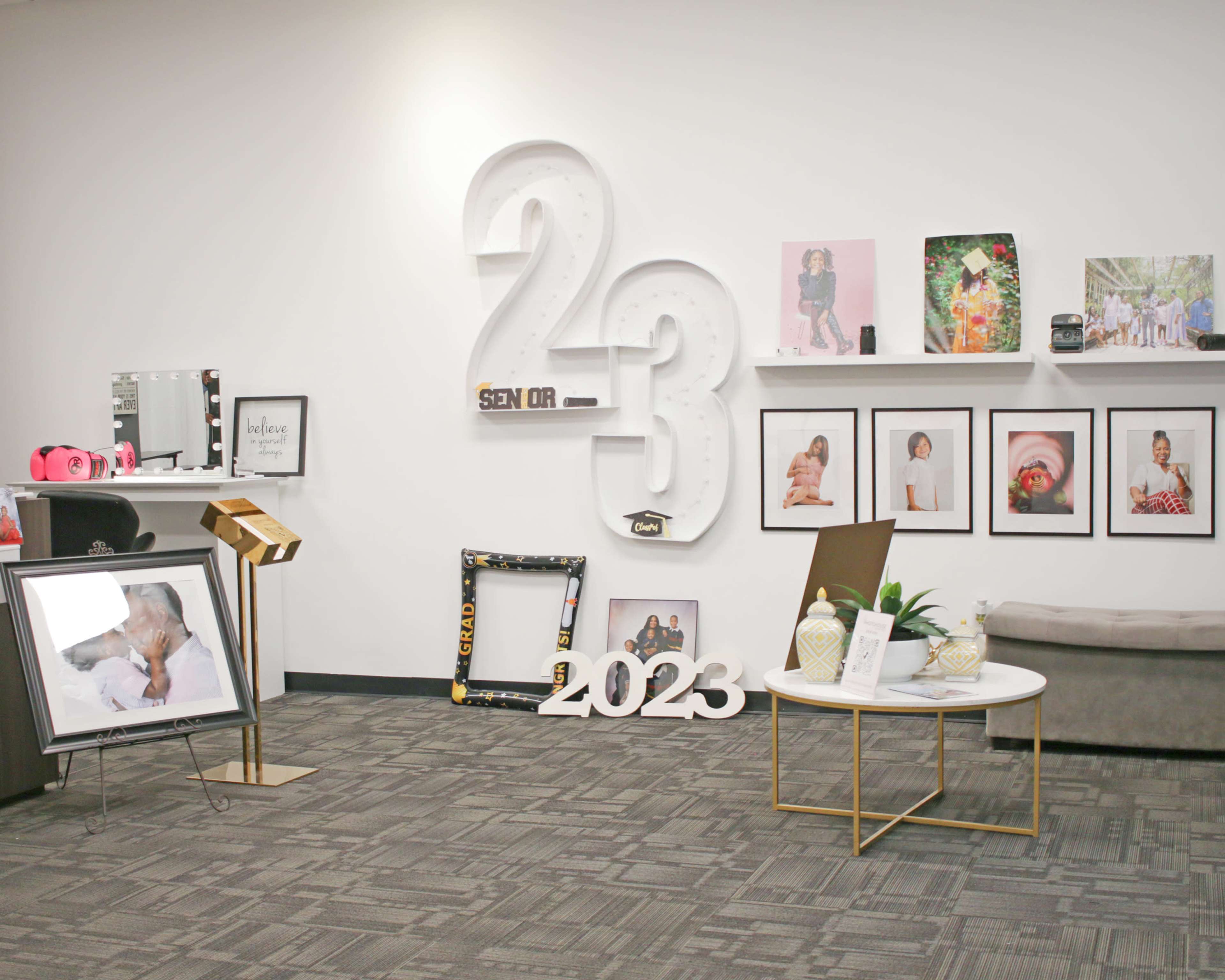 A modern interior space decorated with framed photographs, a coffee table, and large numbers "2" and "3," along with a decorative plant and seating.