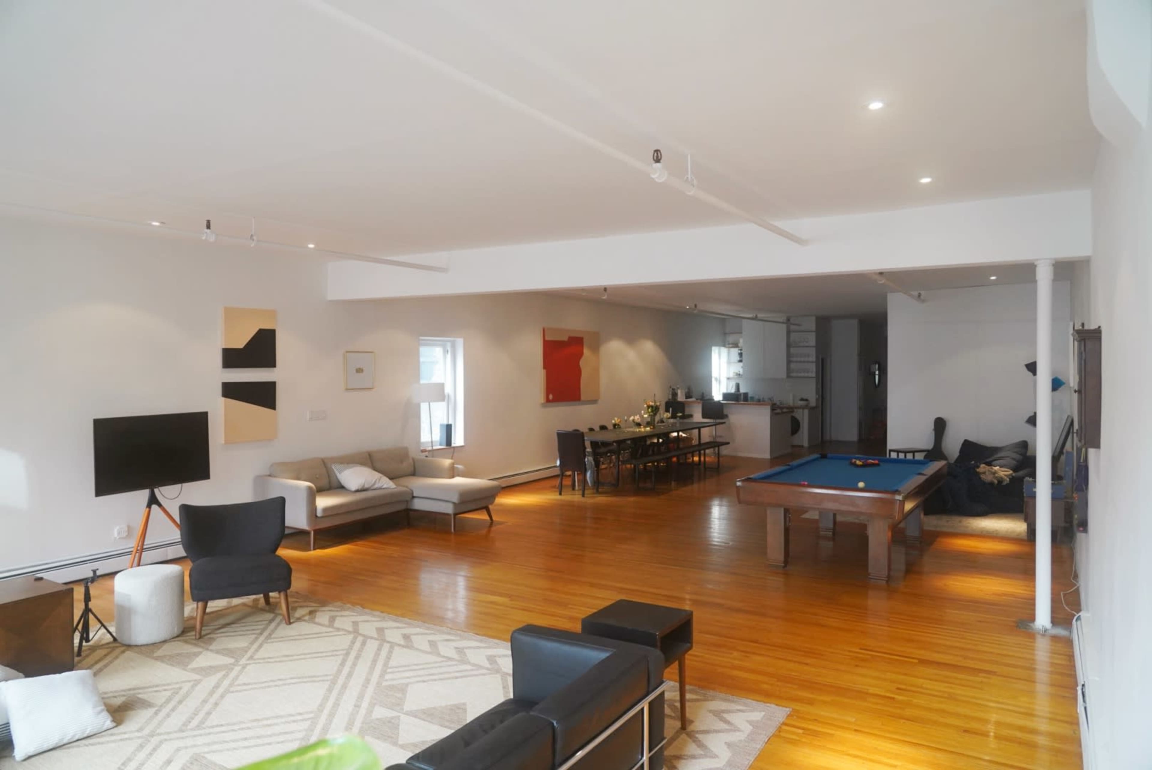 The spacious living area features a pool table, a dining table in the background, and various seating arrangements throughout.