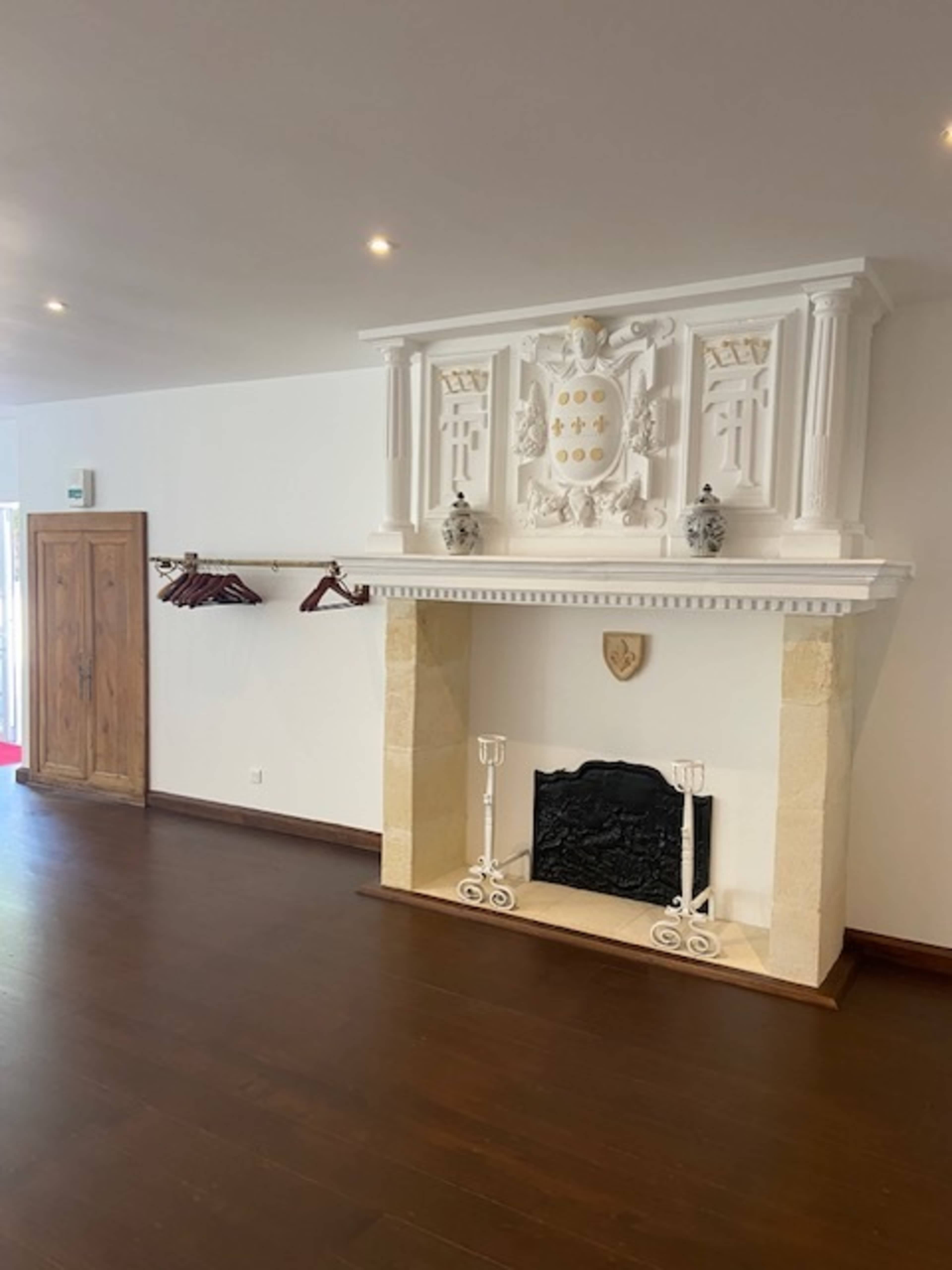A spacious room with a stone fireplace featuring a decorative mantelpiece and a wooden door on the left side.