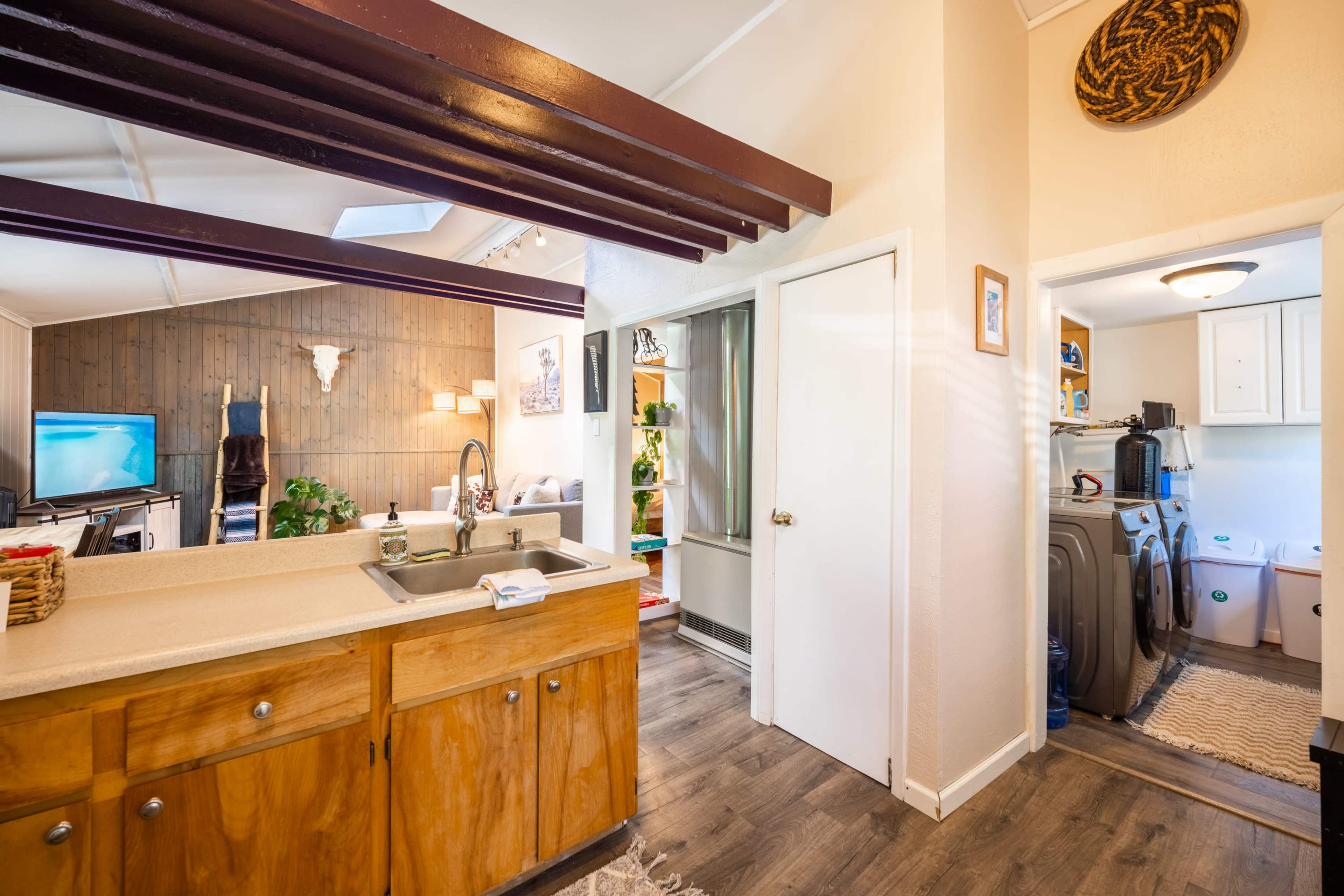 A kitchen area with a wooden countertop, a sink, and a doorway leading to a laundry space.