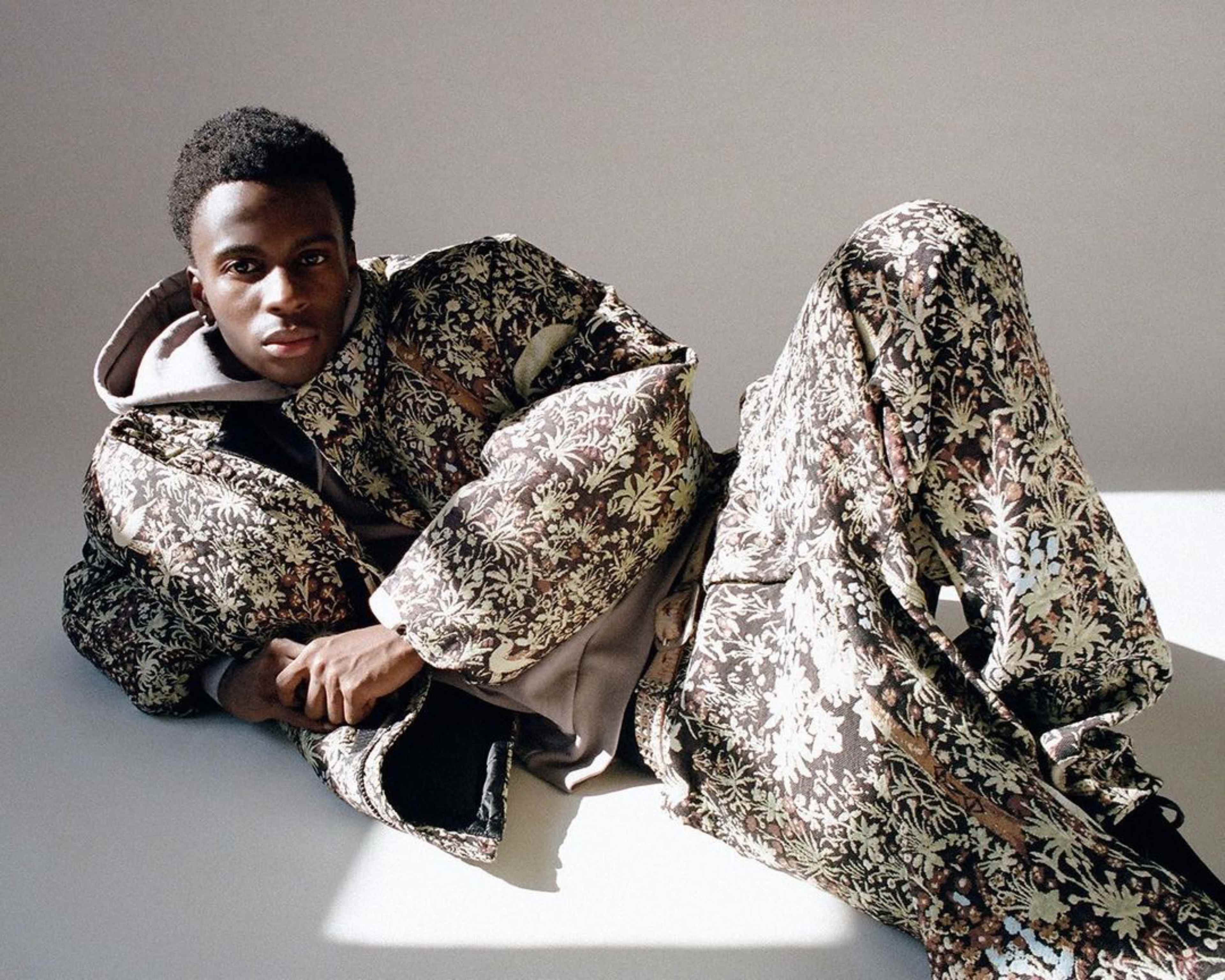 A person in a floral-patterned outfit is reclining on a light-colored surface.