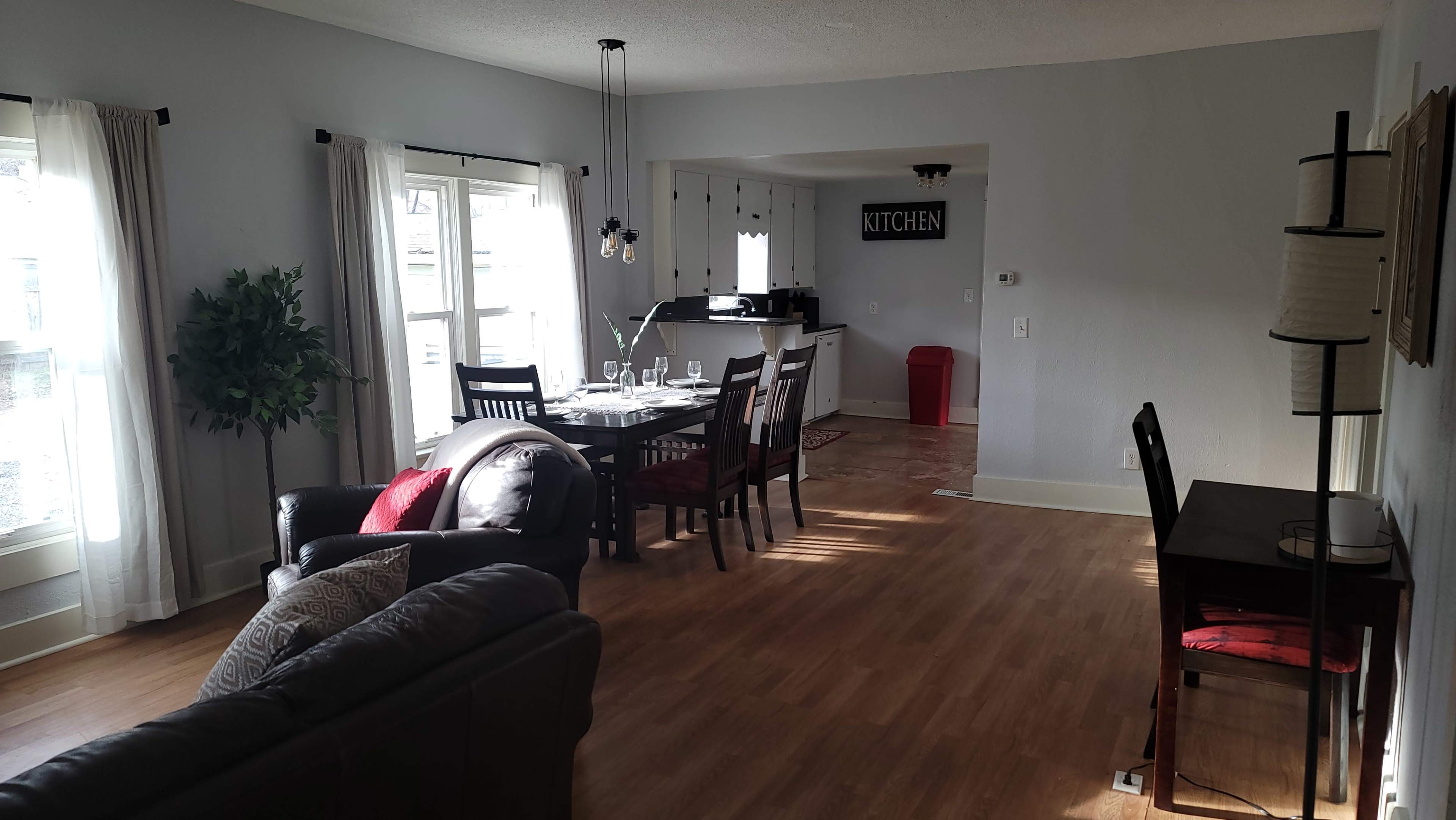 A living area with a dining table, chairs, and a view of a kitchen in an open layout.
