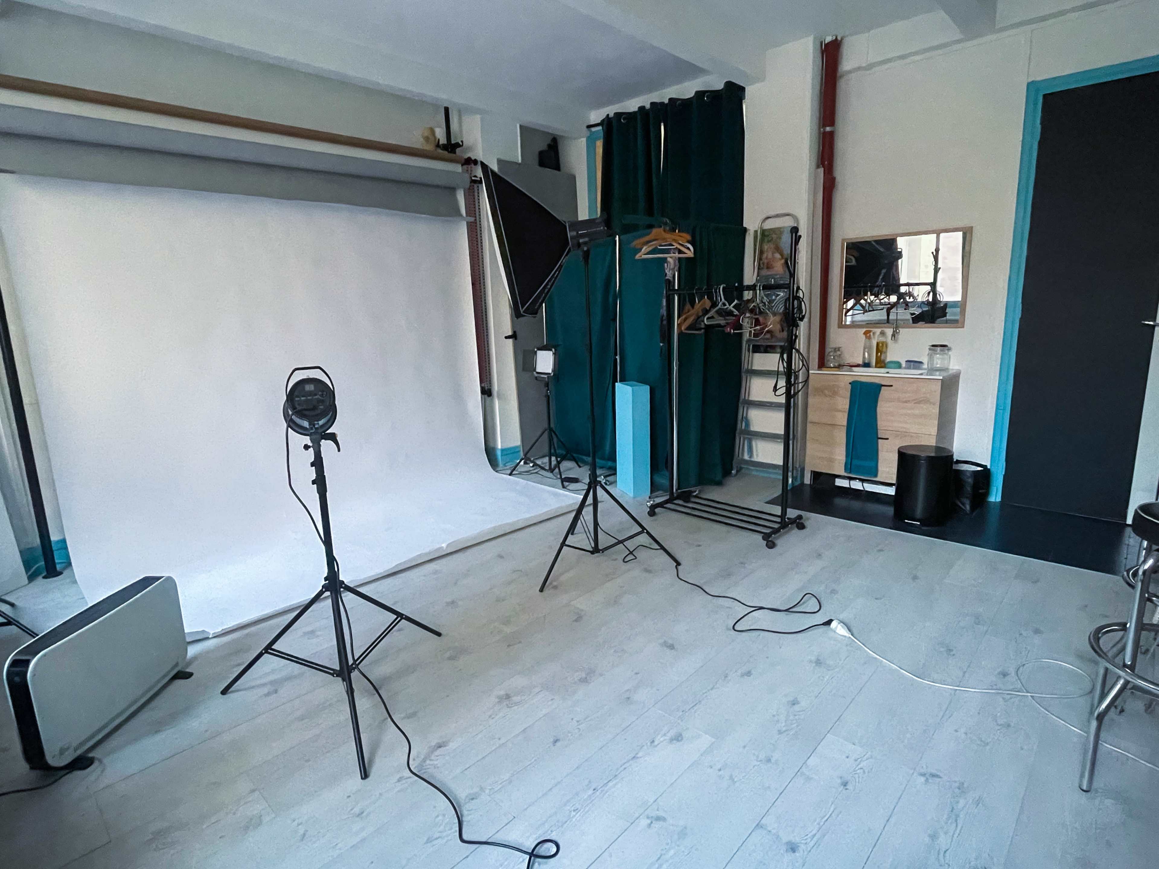 A photography studio set up with a backdrop, lighting equipment, and a mirror on a wooden dresser.