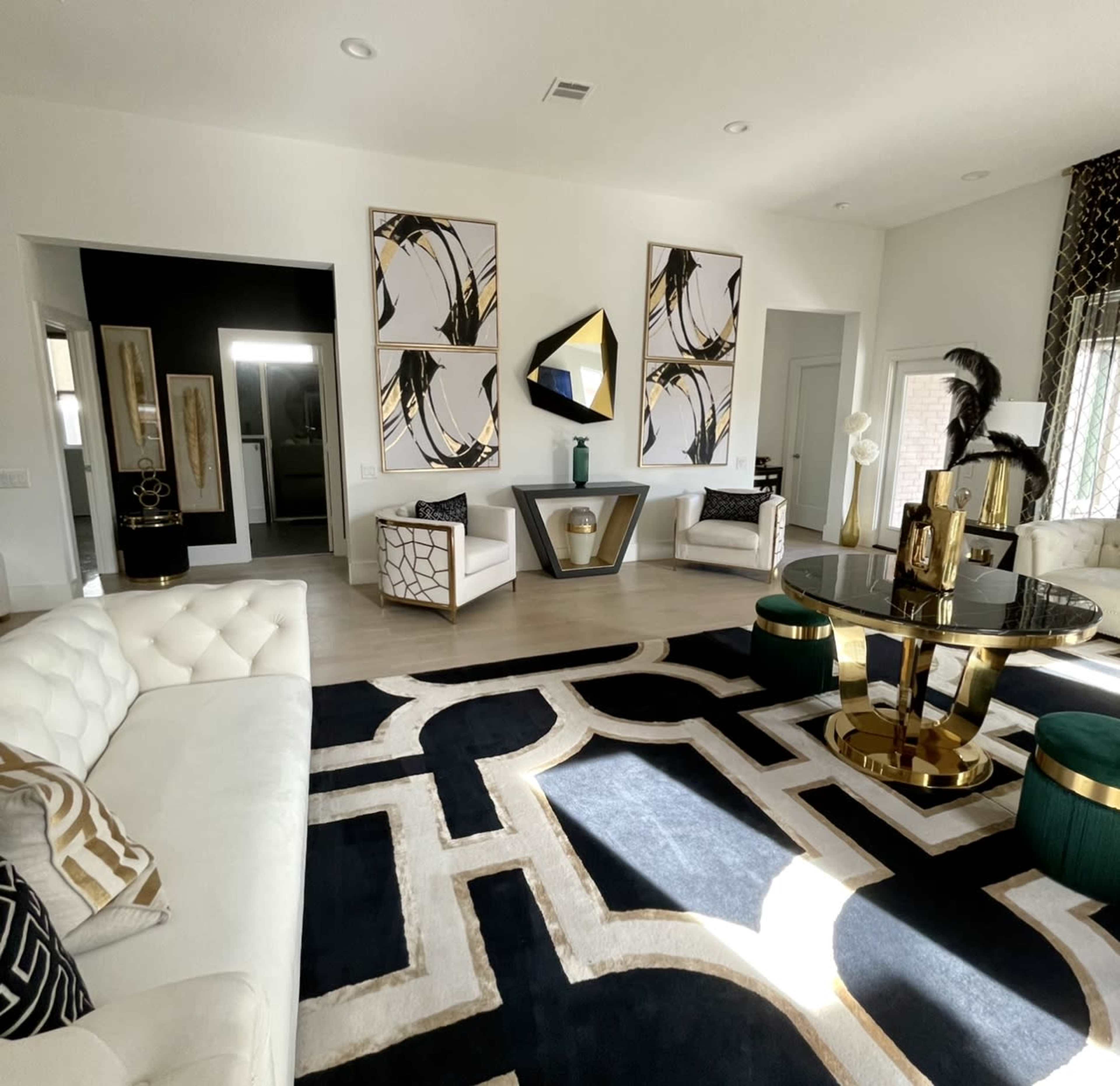 A modern living room featuring a white sectional sofa, a round table, and large abstract art pieces on the walls, complemented by a black and white area rug.