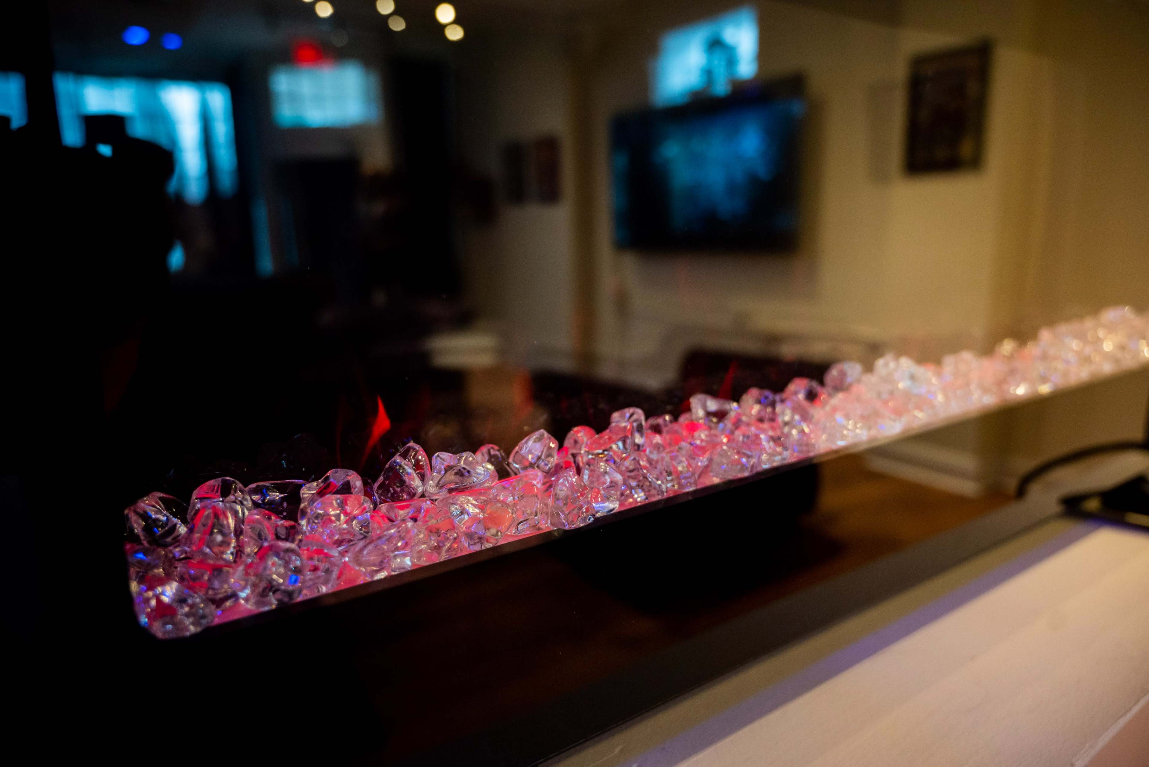 A line of clear decorative crystals, lit by soft red and purple lights, placed in a contemporary setting.